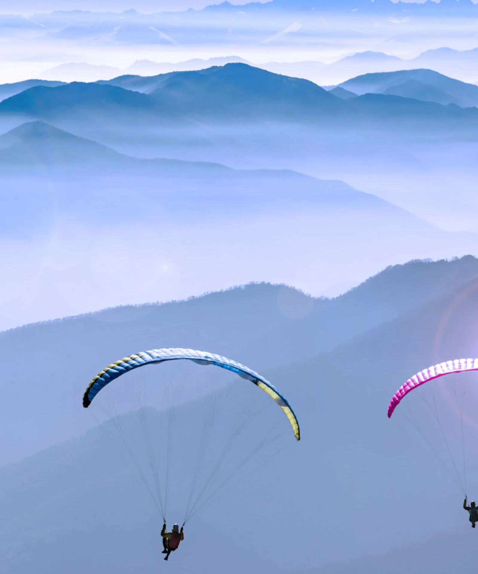 Una imagen inspiradora de dos parapentes volando sobre cadenas montañosas, que representa la transición segura y sin problemas a la tecnología de la nube. Esta imagen refleja el camino recorrido por Honda Bank para acelerar la transformación digital a través de una zona de aterrizaje segura en la nube, con la experiencia de GFT asegurando un proceso de migración seguro y sin problemas.