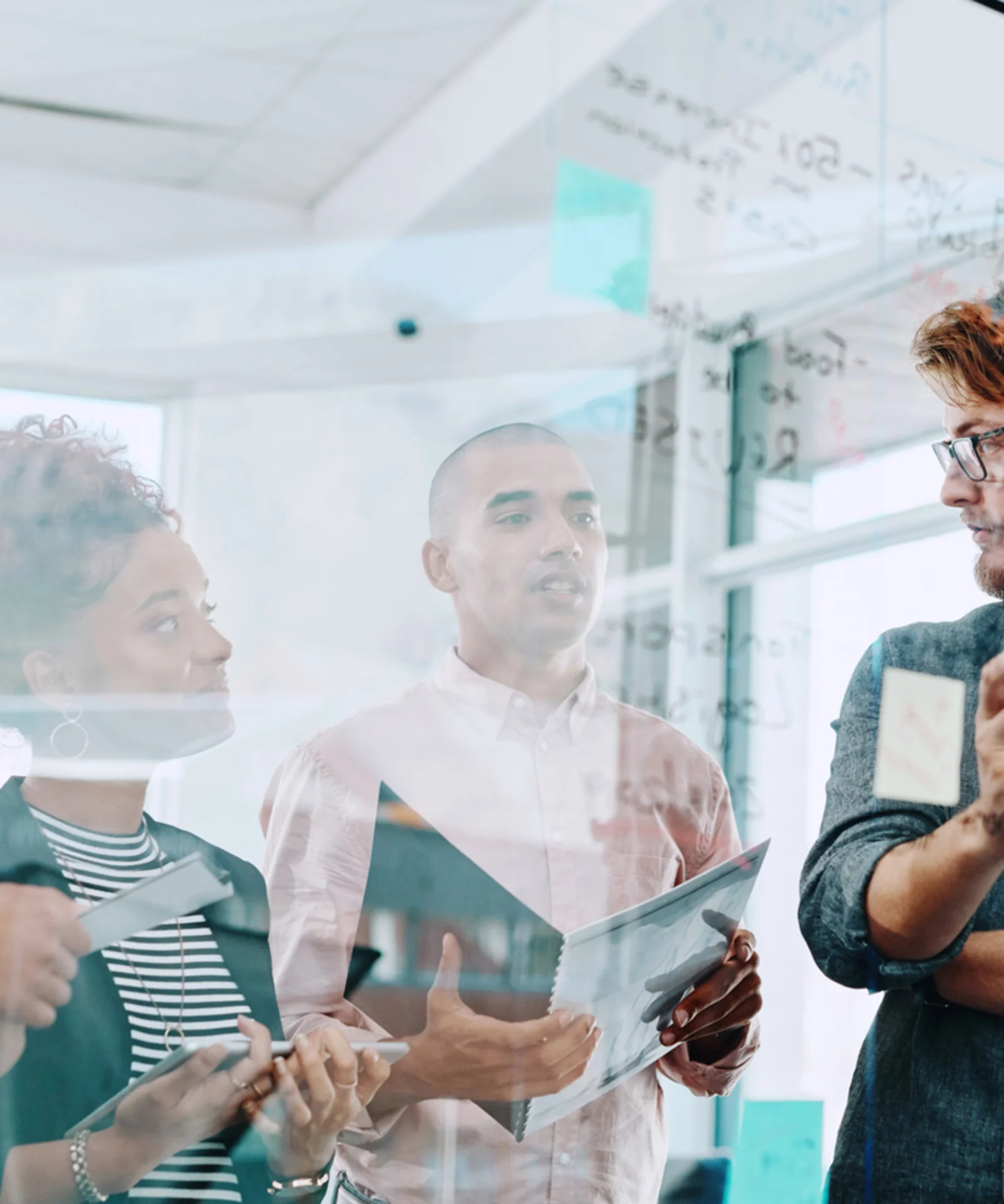 A group of diverse professionals collaborating and brainstorming ideas on a glass board in a modern office setting