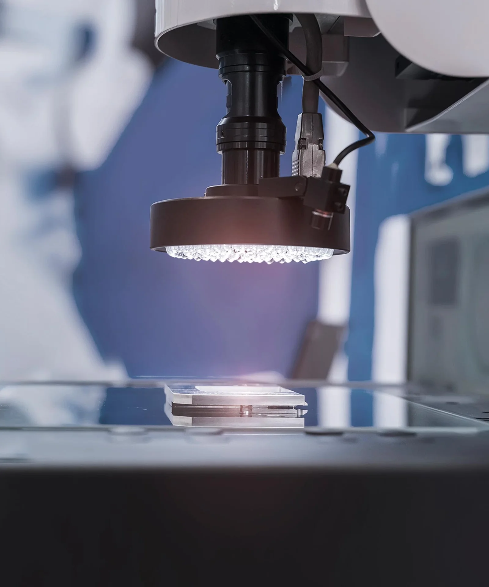 Close-up of a high-tech visual inspection system with a blurred technician in the background, emphasizing precision and advanced technology.