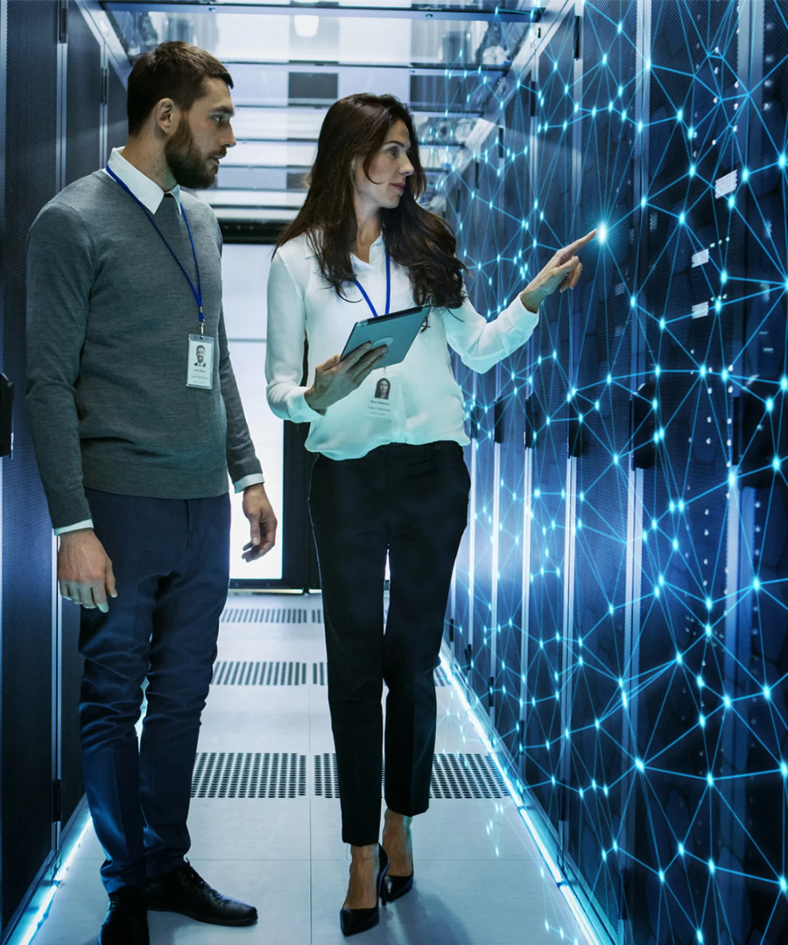 Two professionals in a data centre discussing and analysing a digital network, representing the implementation of a visionary sales platform.