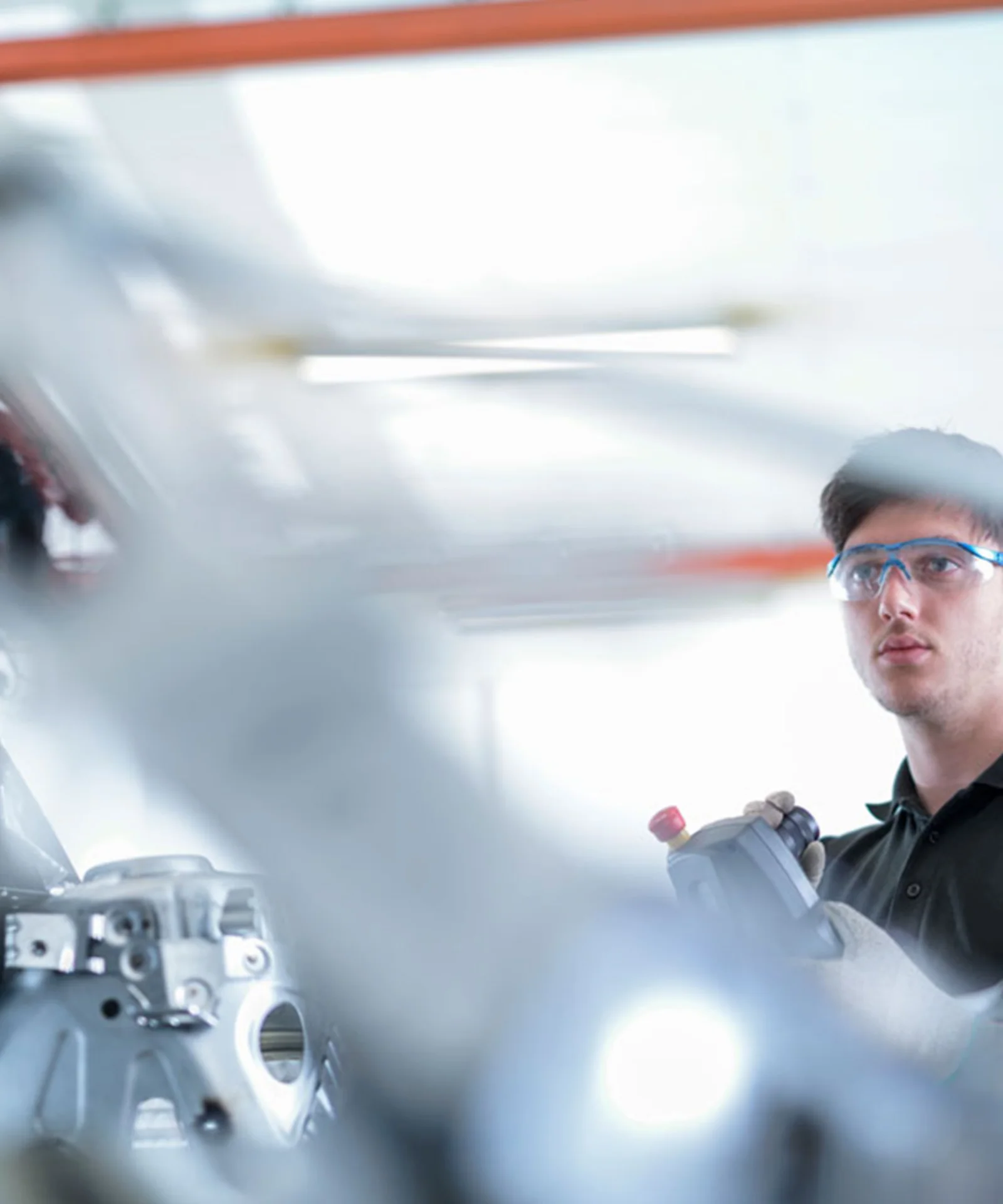 An engineer wearing safety glasses operates advanced machinery in a manufacturing facility, highlighting the integration of IoT technology.