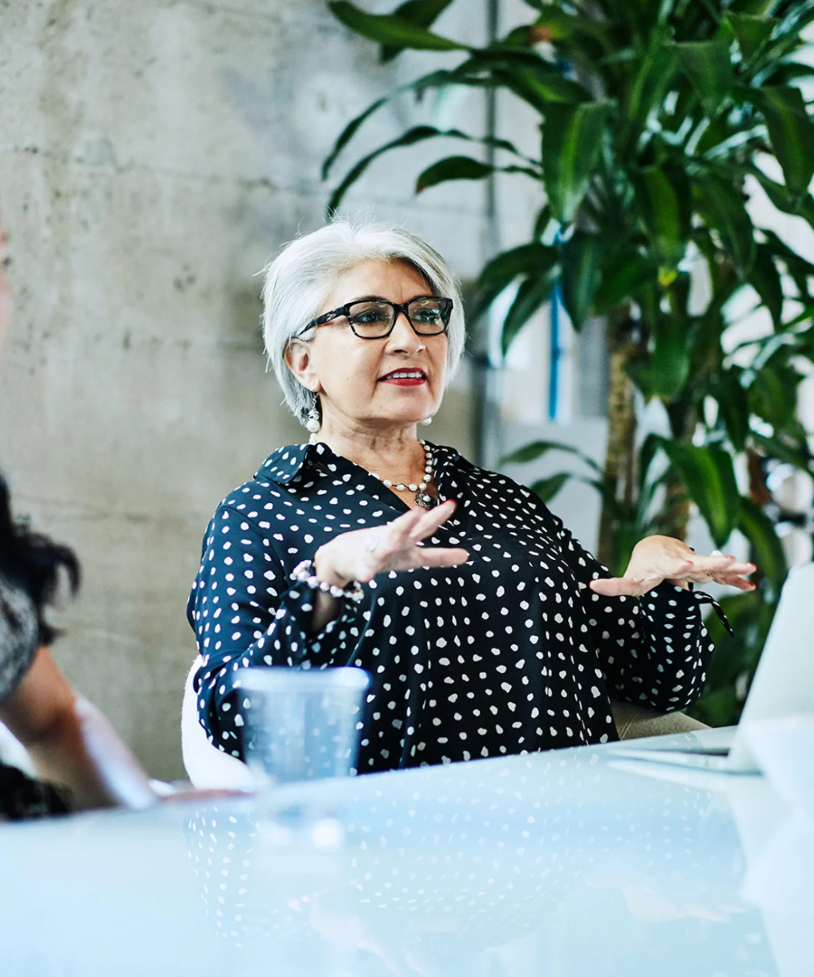 A senior businesswoman leads a collaborative meeting with colleagues, emphasising teamwork and strategic discussion in a modern office setting.