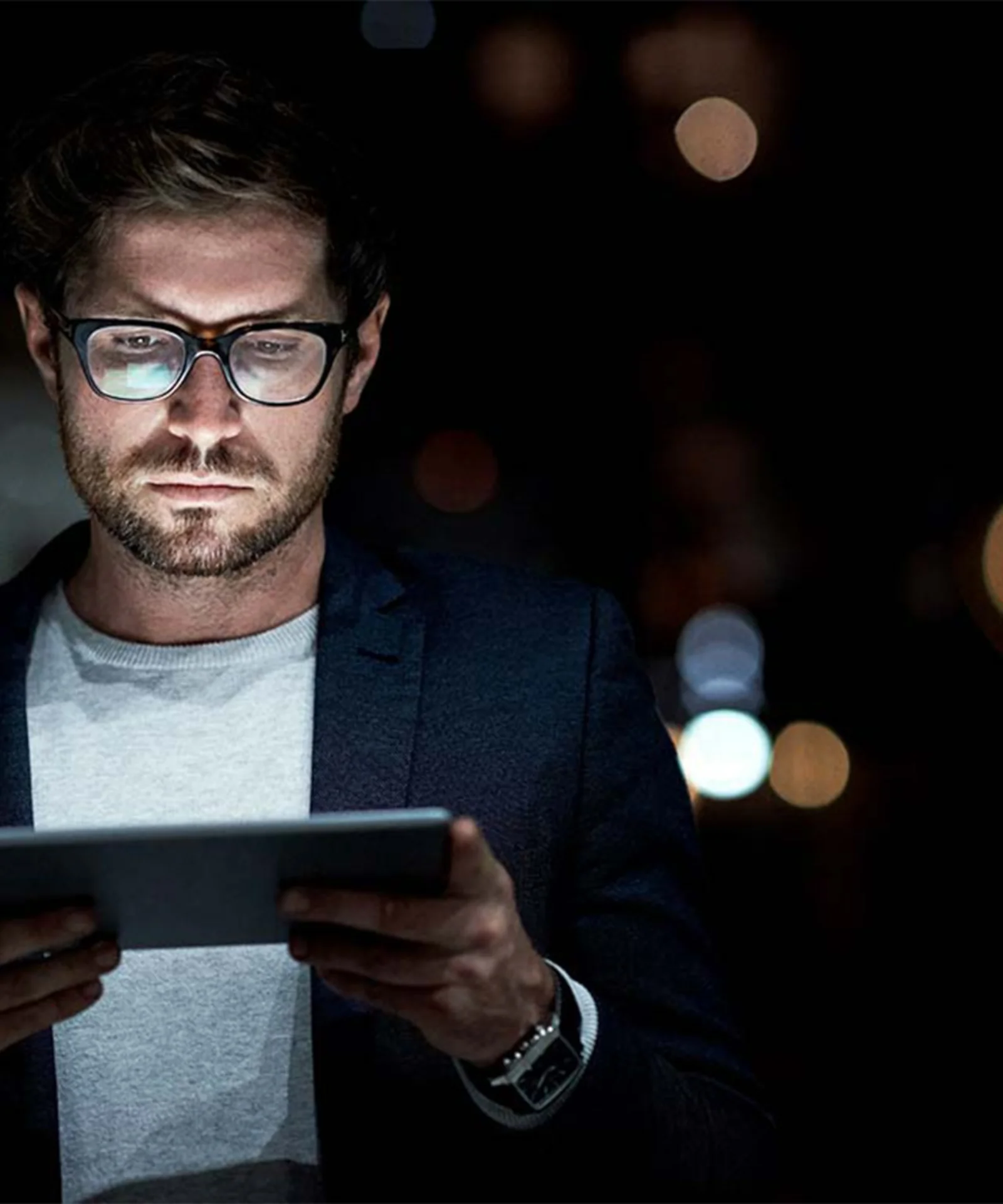 A man using a tablet in a dark environment, symbolising the exploration of DAML smart contracts and custody services in a digital landscape.