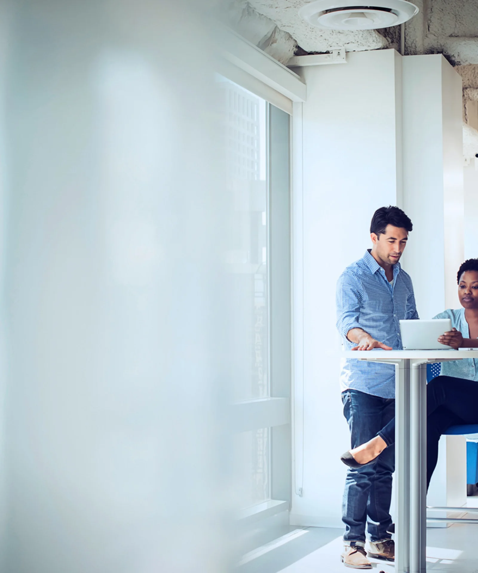 Two professionals collaborating on a laptop in a modern office setting