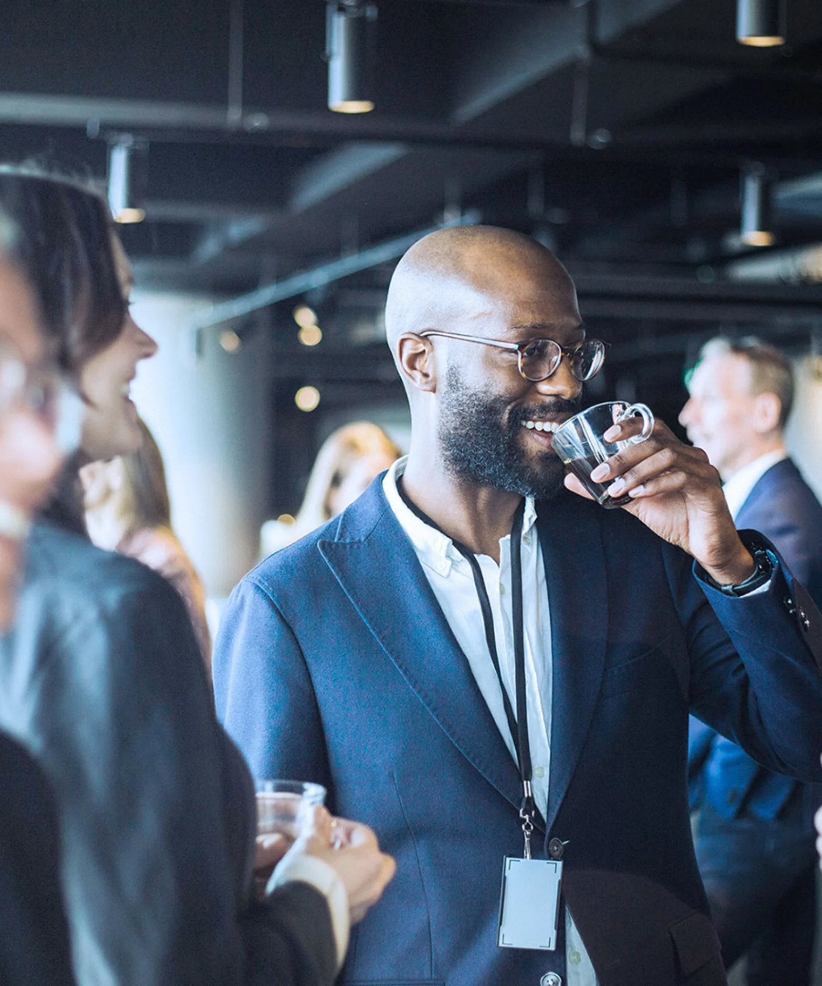 Professionals engaging in conversation and networking at a GFT event, with one man drinking coffee and others smiling and talking.