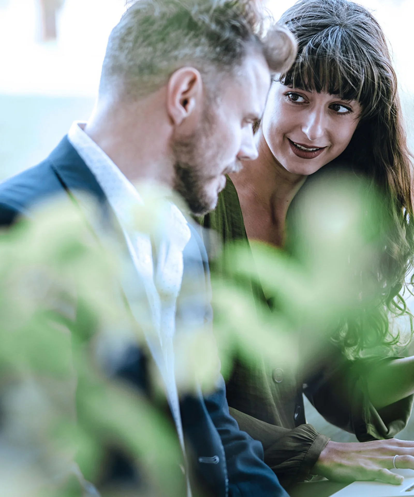 A man and a woman engaged in a focused discussion outdoors, with lush greenery surrounding them, symbolizing transparency and ethics in business practices.