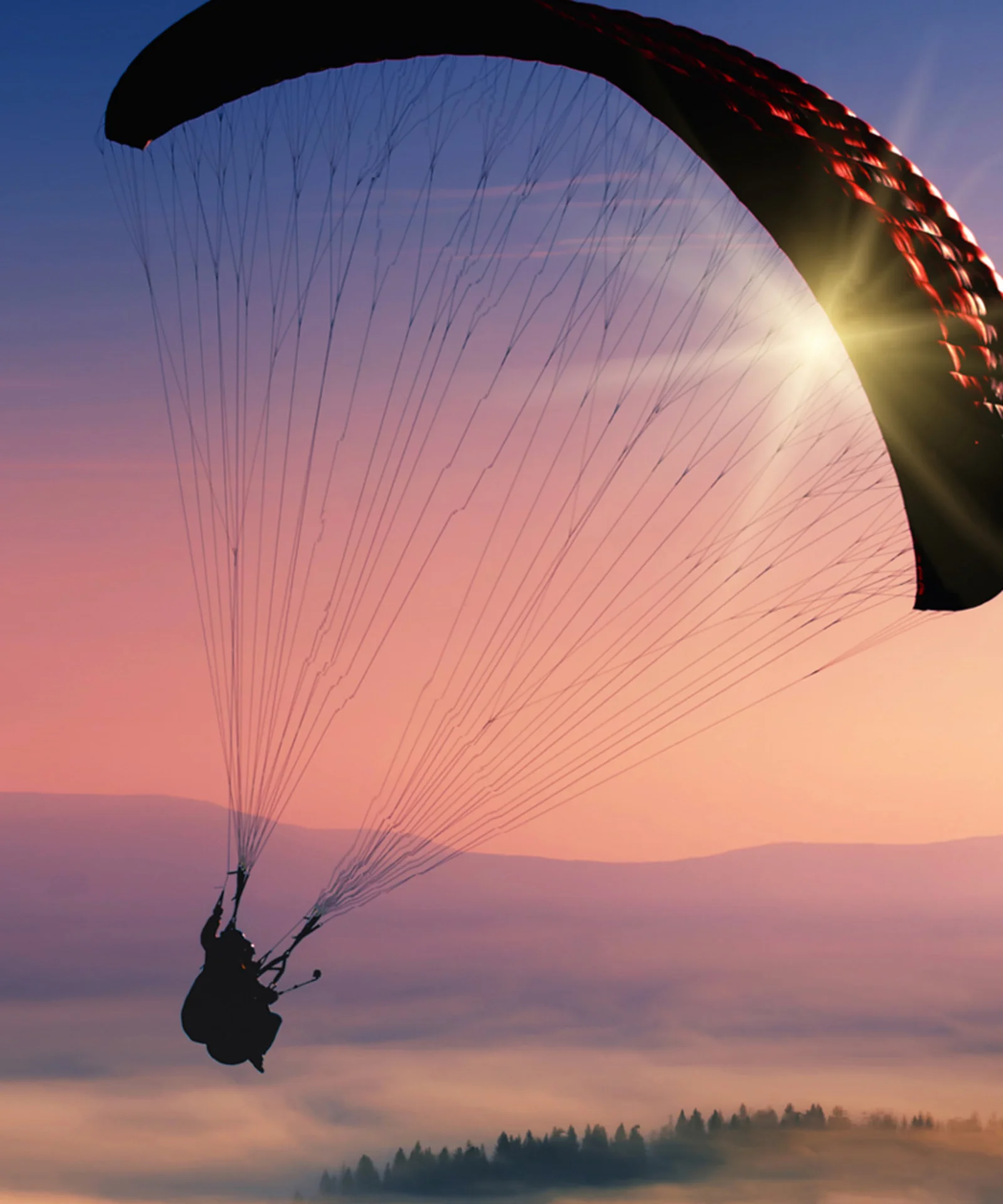 A breathtaking silhouette of a paraglider soaring through a vibrant sunset sky, symbolising the freedom, agility, and expansive possibilities offered by hybrid and multicloud solutions.