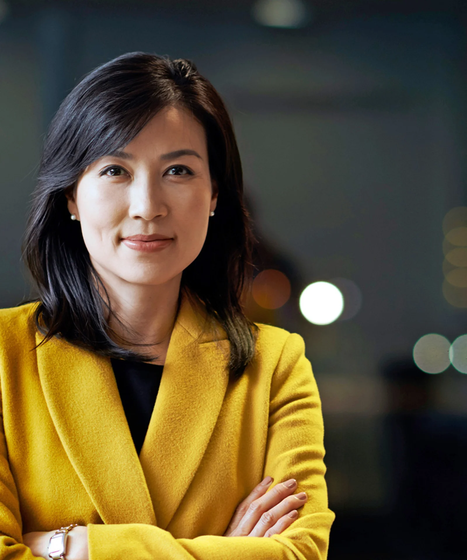 Confident professional woman in a yellow jacket with arms crossed, representing executive leadership.