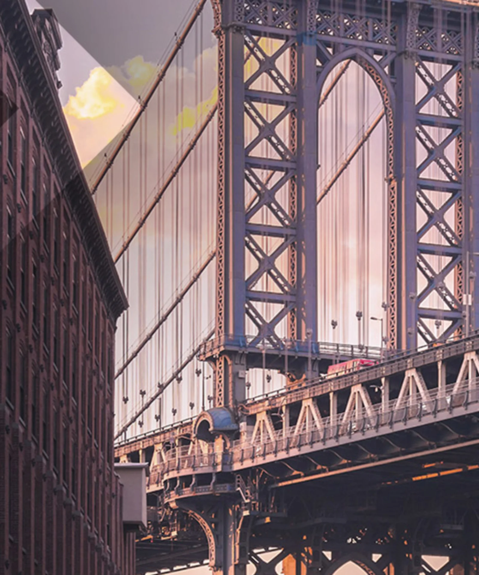 A view of the Manhattan Bridge framed by tall urban buildings at sunset, showcasing the architectural beauty and urban landscape of New York City.