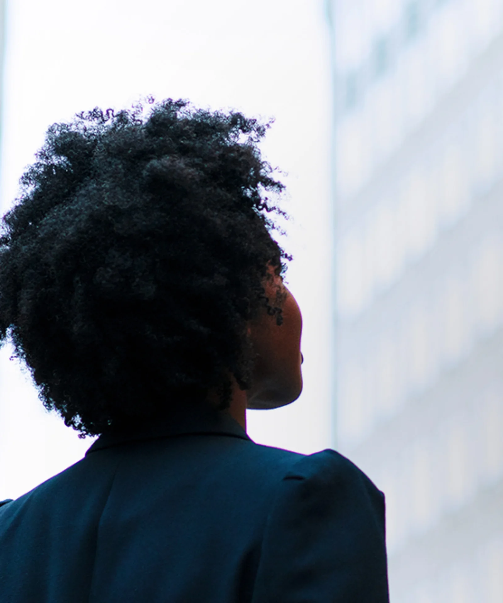 Headerbild zeigt eine Person von hinten, die vor modernen Gebäuden steht. Symbolbild für Veränderungen, Effizienz und Innovation durch T+1 im Finanzsektor.