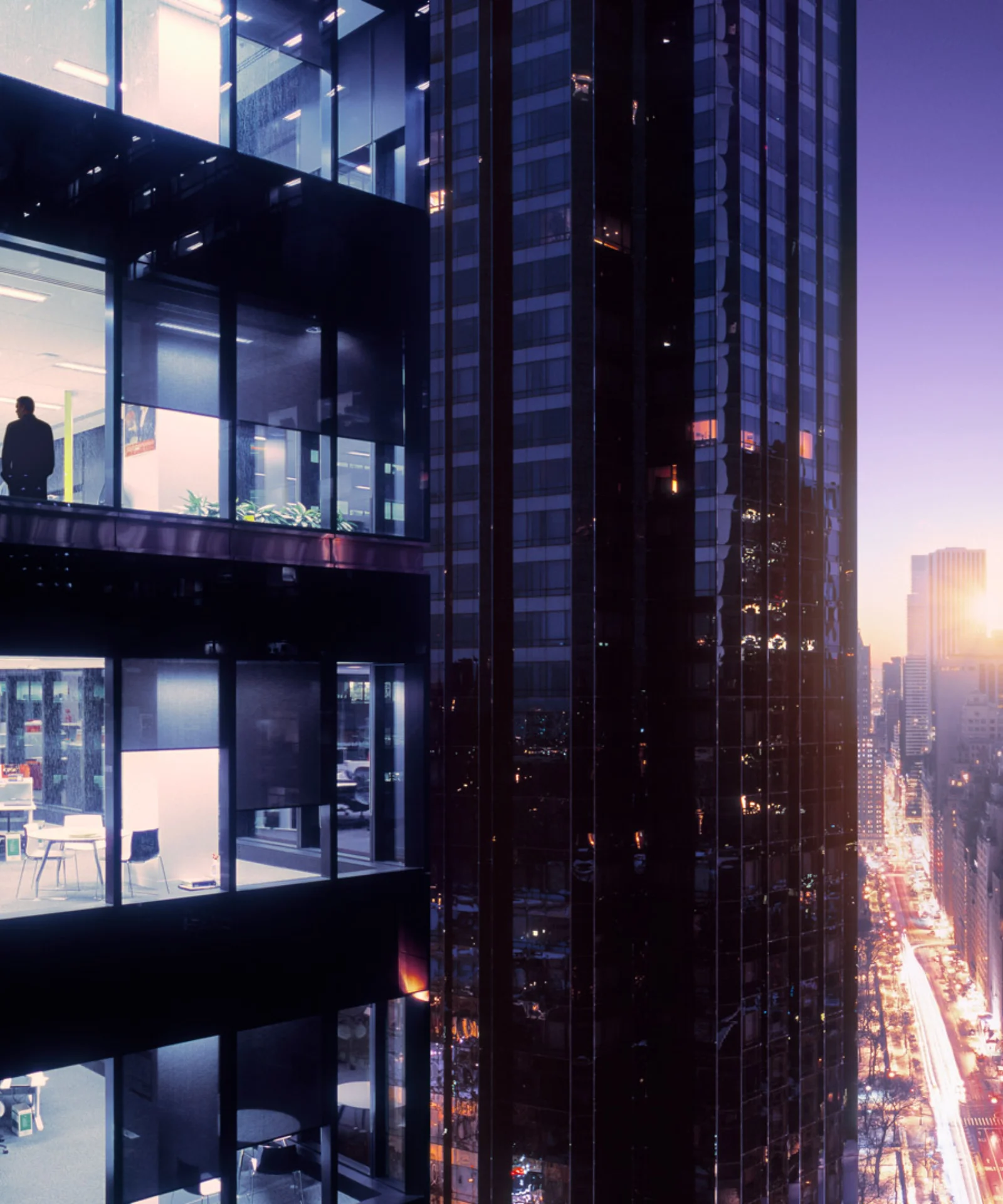 A cityscape at dusk with illuminated office buildings, one with a silhouette of a person inside, representing the evolving landscape of digital banking and financial services.