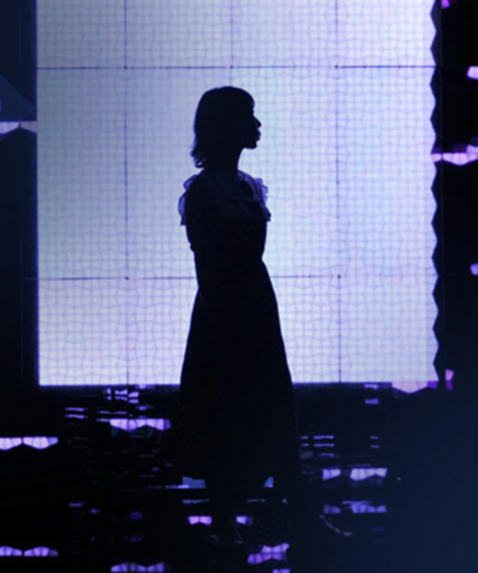 Silhouette of a person standing against a background of digital lights and screens, representing the intersection of technology and human presence in a digital world.