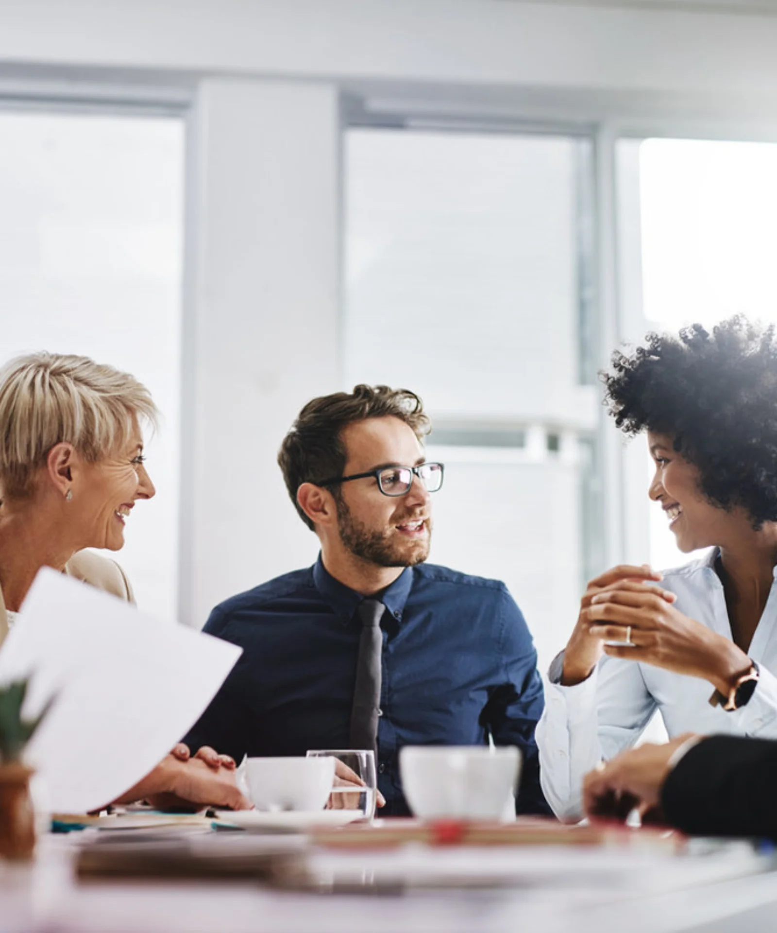 A diverse group of professionals engaging in a lively discussion during a meeting, symbolising teamwork, collaboration, and shared innovation in a bright office setting.