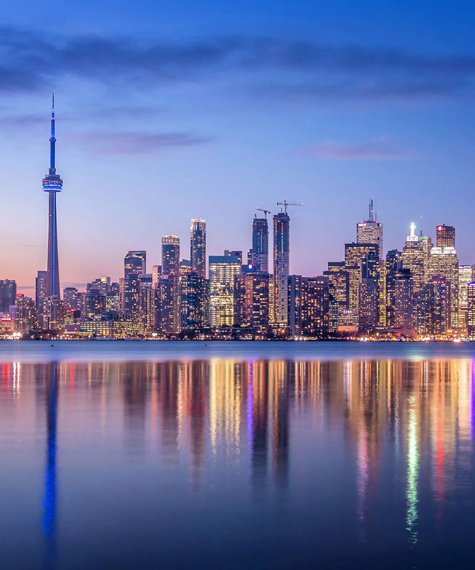 City skyline at dusk with reflections on the water, symbolizing stability and the future of the insurance industry.