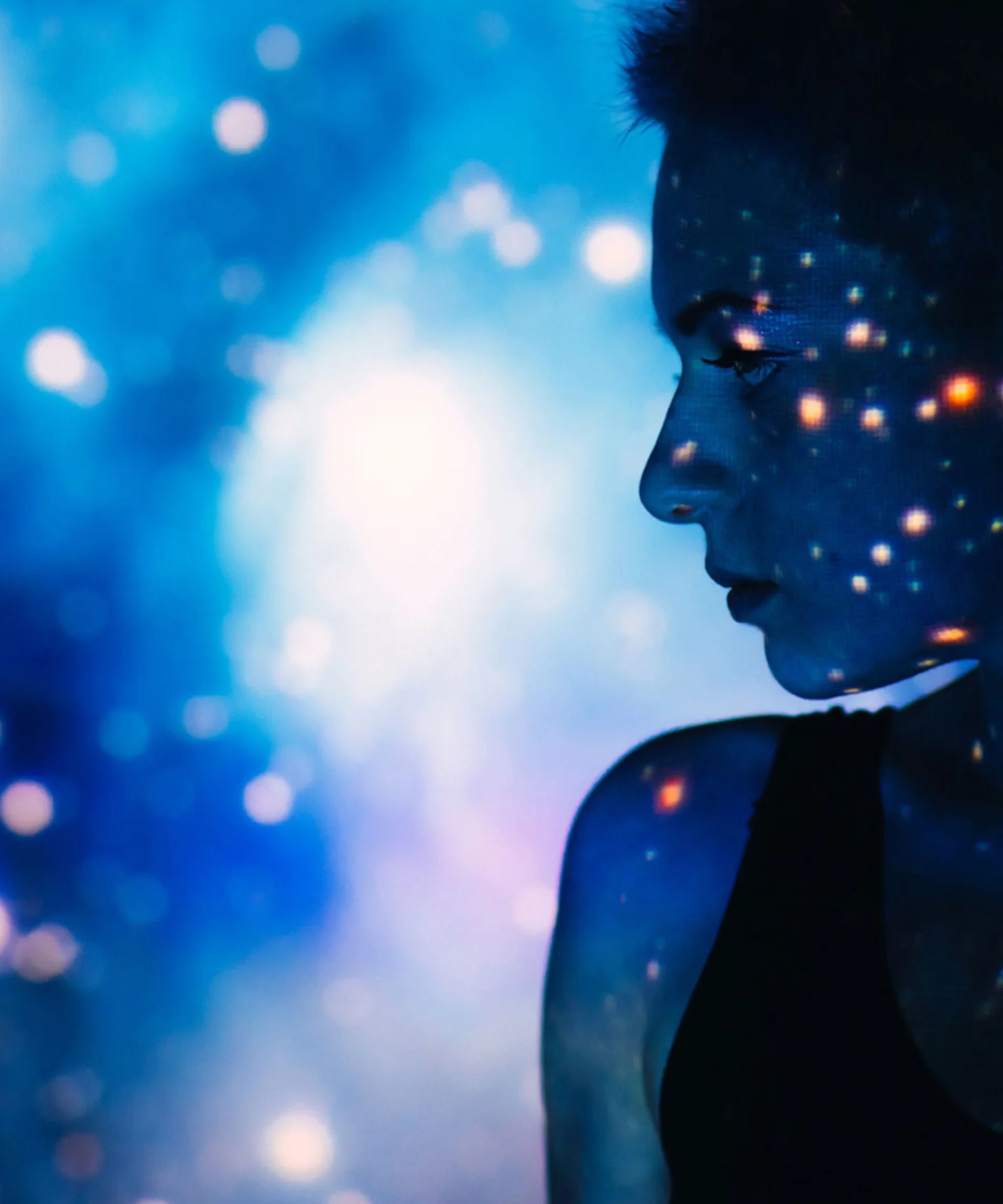 A silhouetted profile of a person with a digital starry projection on their face and background, symbolising the power and creativity of artificial intelligence.