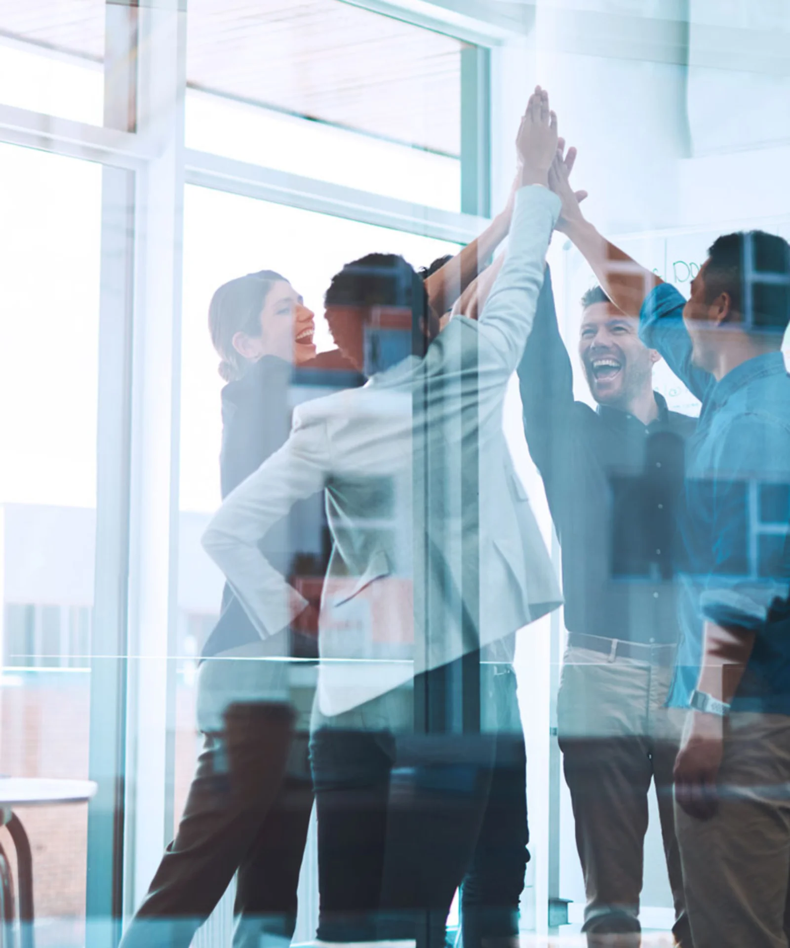 A team of professionals celebrating a successful project in a bright, modern office space, with a whiteboard in the background showcasing project plans and progress.