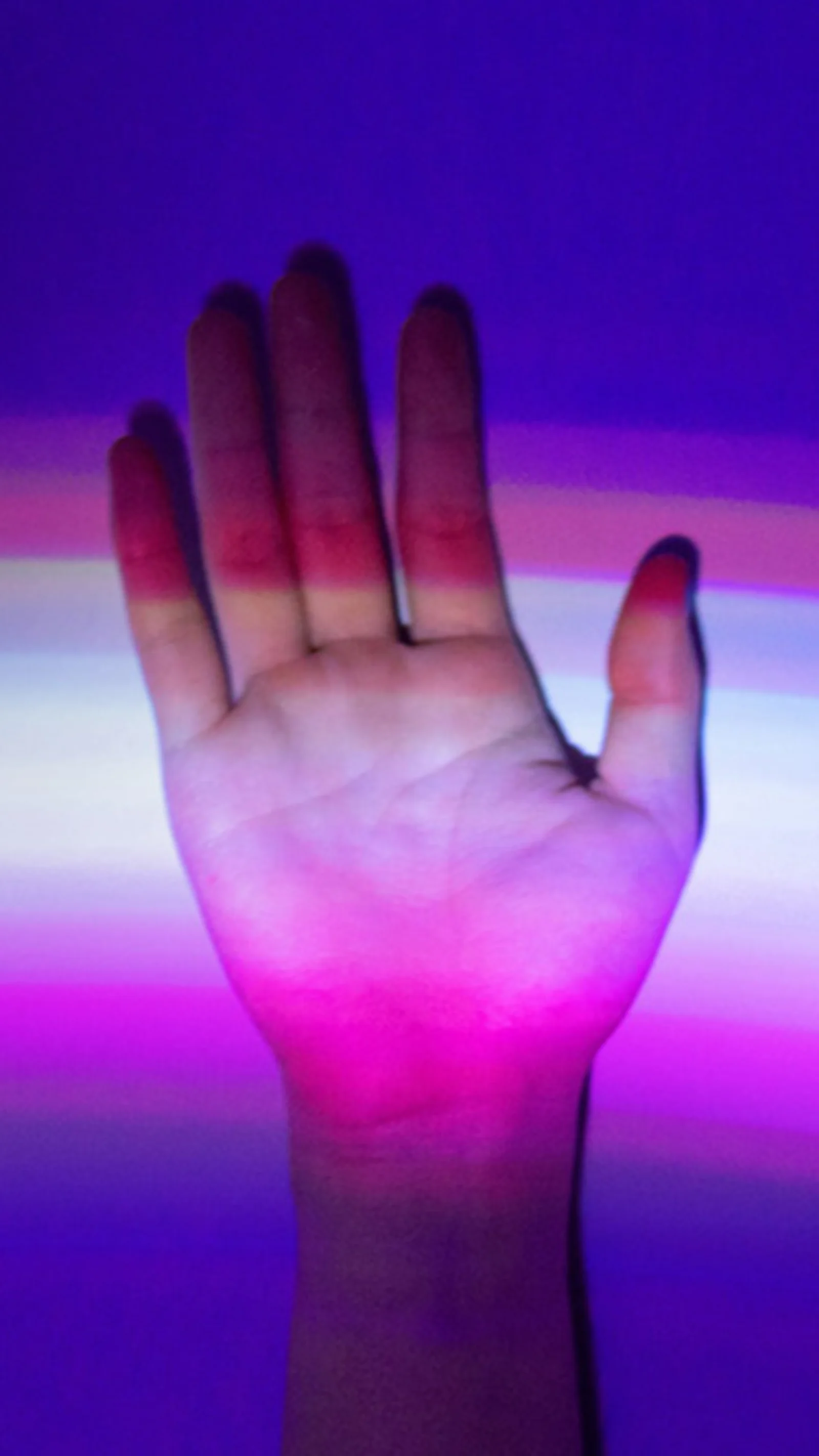 Hand raised against a background of colorful light streaks, symbolizing the connection between human interaction and digital technology.