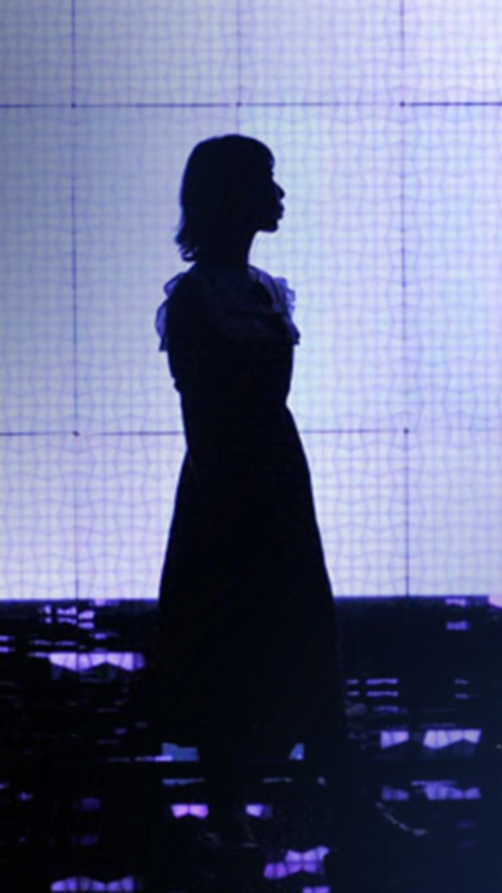 Silhouette of a person standing against a background of digital lights and screens, representing the intersection of technology and human presence in a digital world.