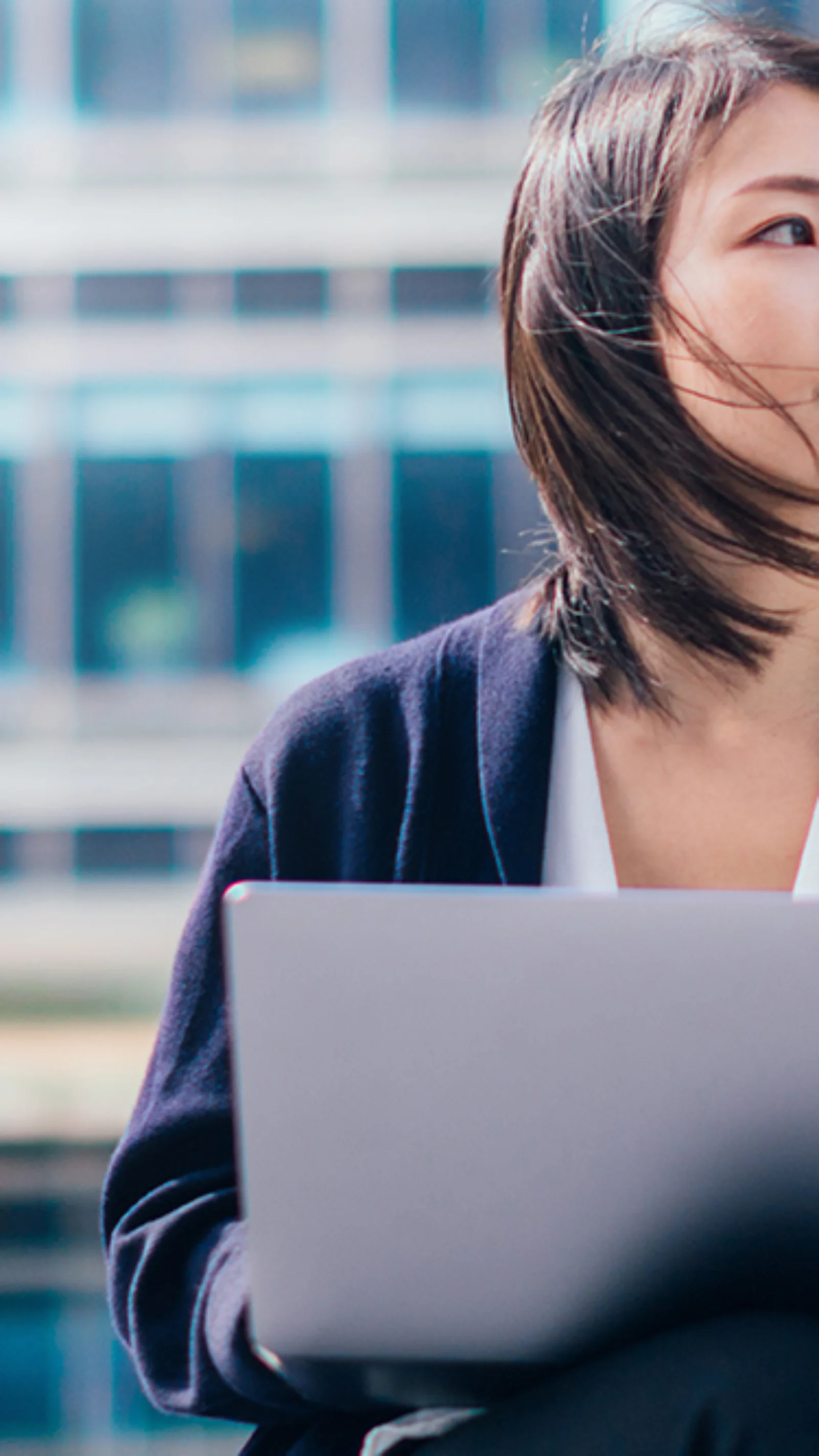 Headerbild einer Geschäftsfrau mit Laptop vor einem modernen Bürogebäude. Symbolisiert die T+1-Roadmap und die digitale Transformation der Finanzmärkte in Europa.