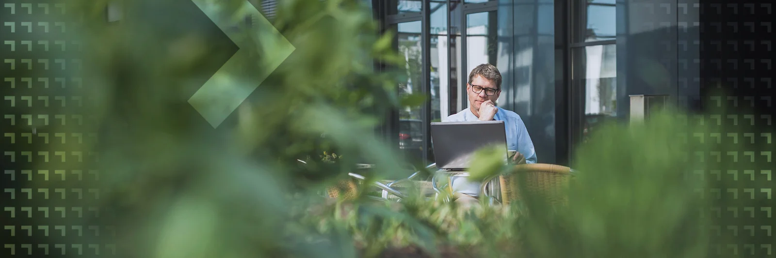 Das Bild zeigt einen Mann, der konzentriert an einem Laptop arbeitet. Er ist von zahlreichen grünen Pflanzen umgeben, die eine natürliche und beruhigende Atmosphäre schaffen. Die Szene symbolisiert das Thema Nachhaltigkeit und verbindet technologische Arbeit mit einer umweltfreundlichen Umgebung. Es dient als Key Visual für einen Blogbeitrag, der sich mit Nachhaltigkeit in der Finanzwirtschaft auseinandersetzt.