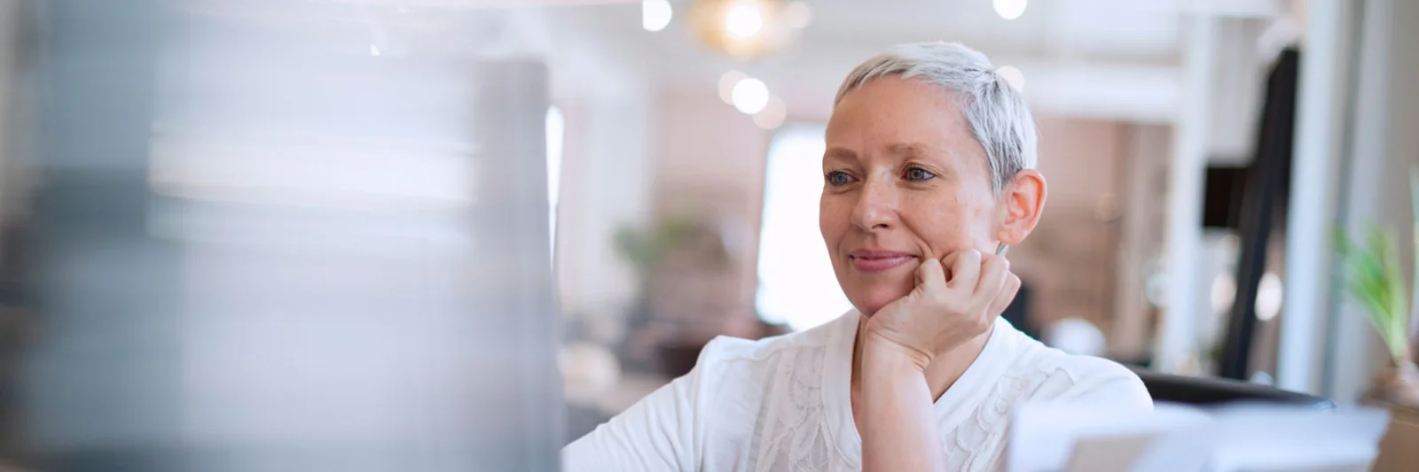 Smiling professional woman working at her desk in an office, representing the transformation of HR with AI chatbots.