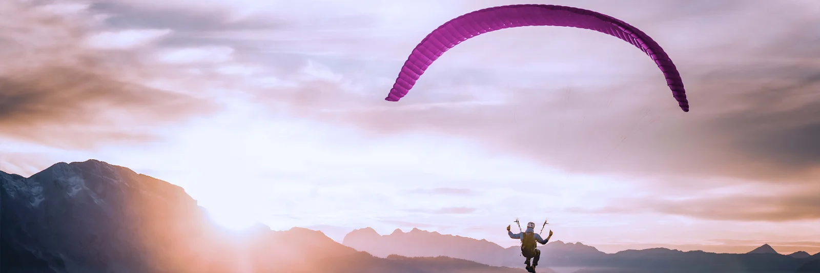 Ein Paraglider schwebt über den Wolken bei Sonnenaufgang, symbolisiert die Flexibilität und Freiheit in der Cloud-Nutzung, während gleichzeitig die Kontrolle über Kosten erhalten bleibt.