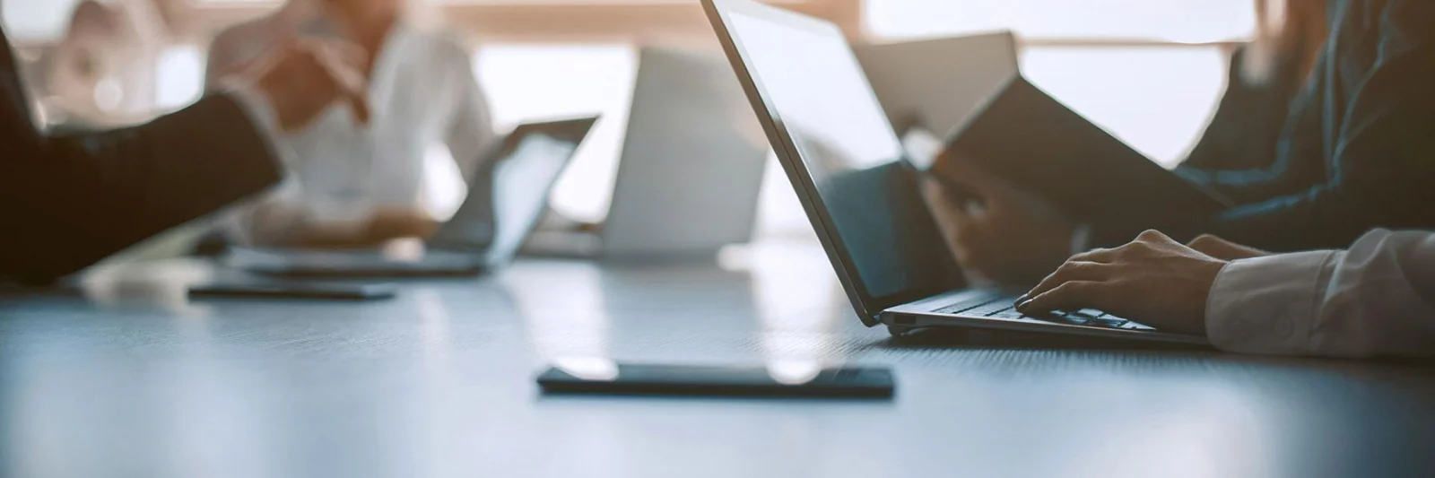 Business professionals working on laptops in a meeting room, focusing on secure and connected AWS cloud solutions.