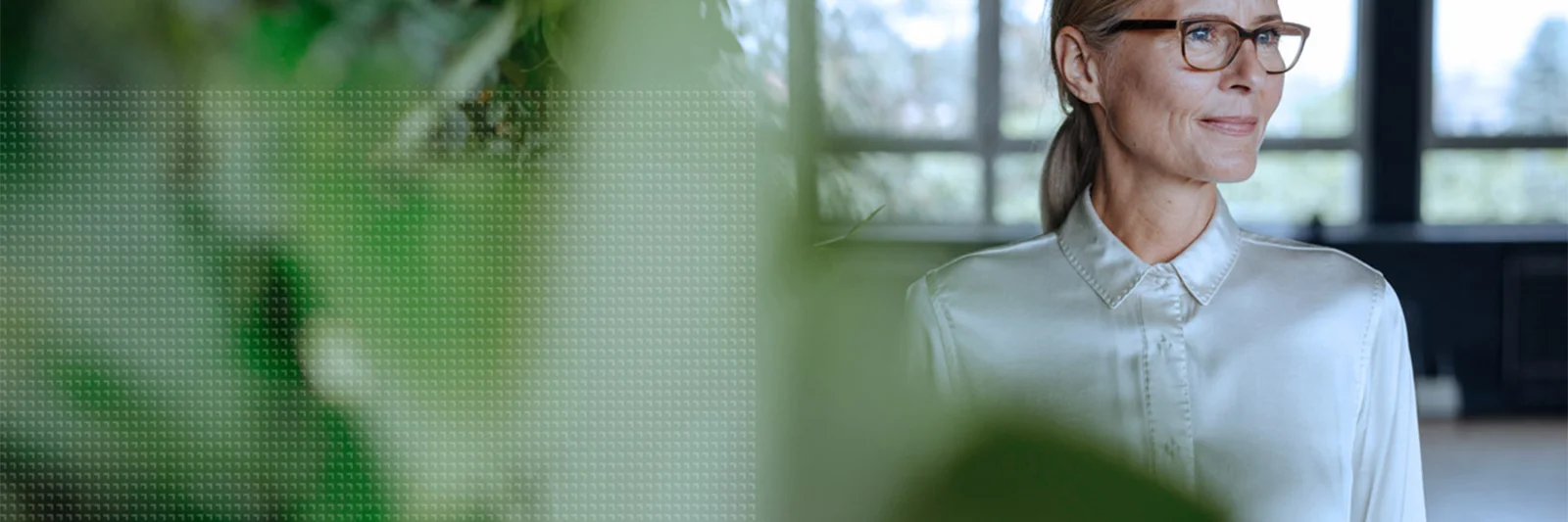 A professional woman in glasses and a white blouse standing confidently in an office environment with green plants, symbolizing GFT&#039;s commitment to corporate governance and ethical leadership.