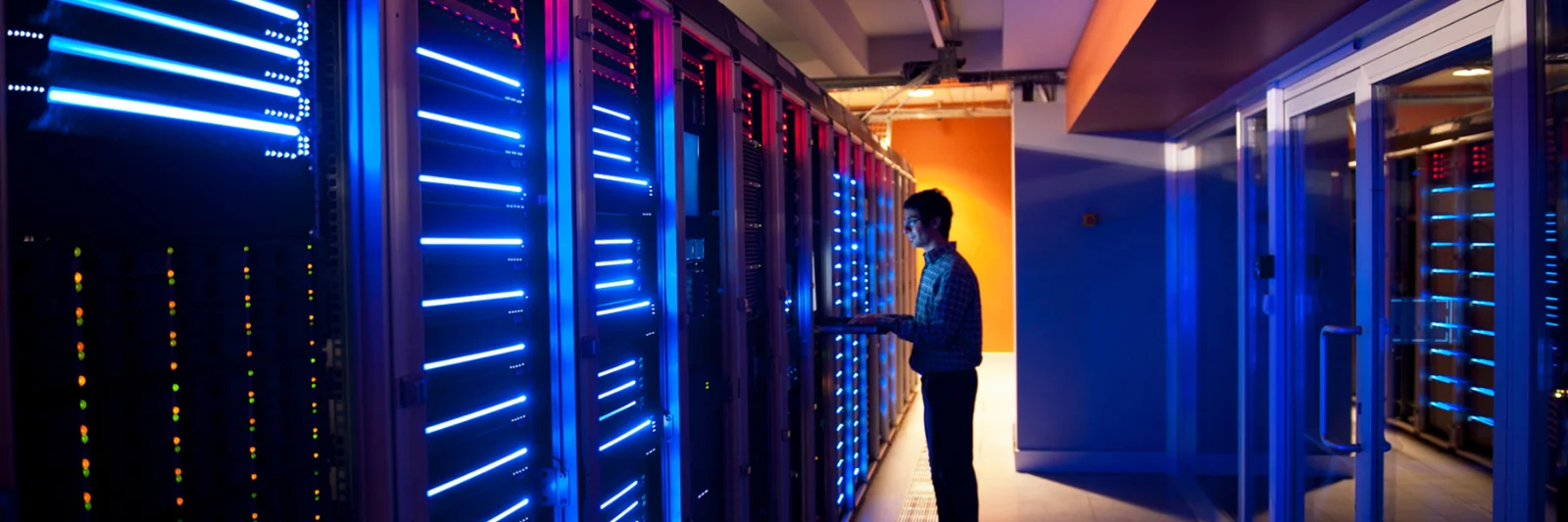 Technician working in a data centre with blue and red illuminated servers