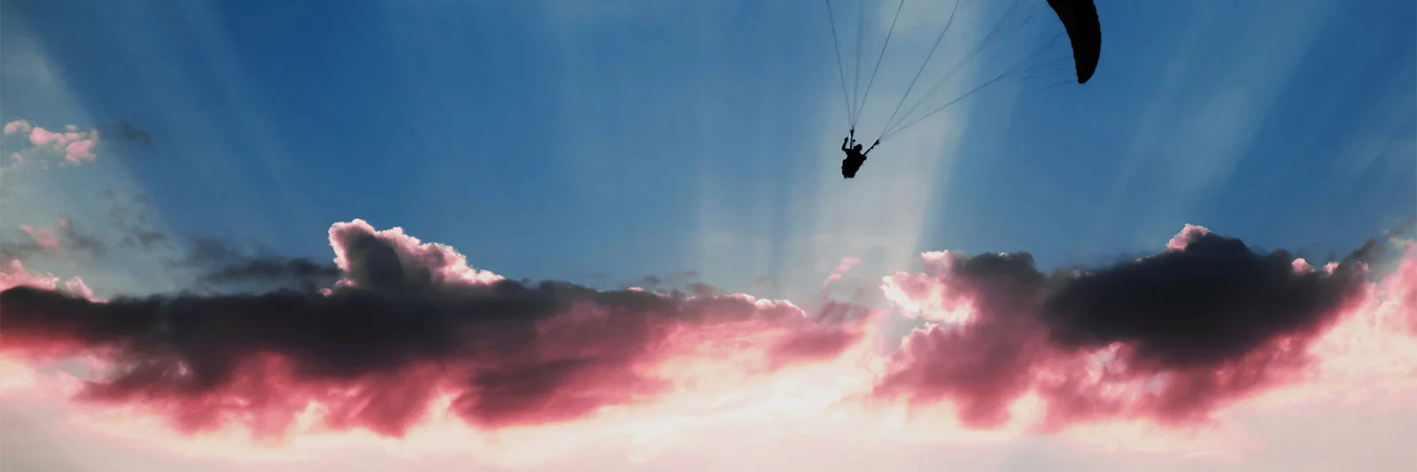 A silhouette of a paraglider soaring against a stunning sunset sky, symbolising the freedom, scalability, and innovation offered by cloud computing.