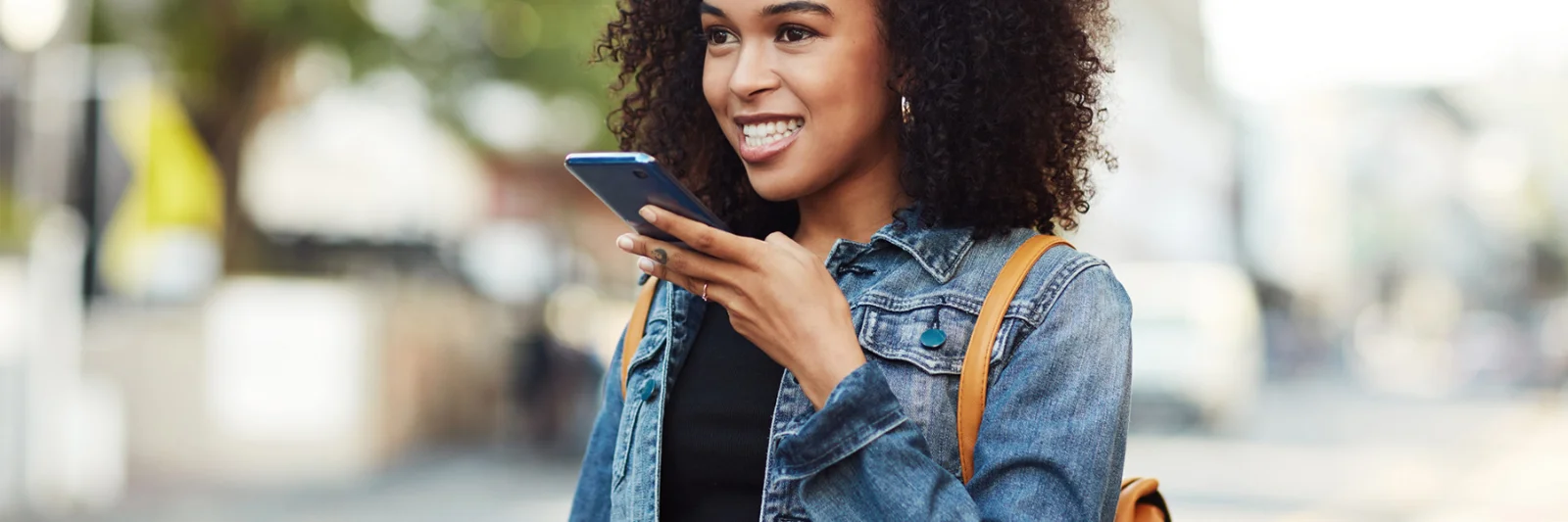 Una mujer joven que usa comandos de voz en su teléfono inteligente, lo que representa un servicio al cliente mejorado a través de la integración de Google Assistant.