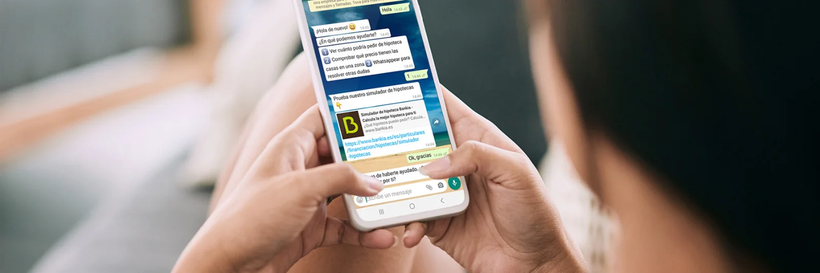 Una persona utiliza un teléfono inteligente con un chat de WhatsApp abierto, demostrando el uso de WhatsApp como canal digital de atención al cliente.