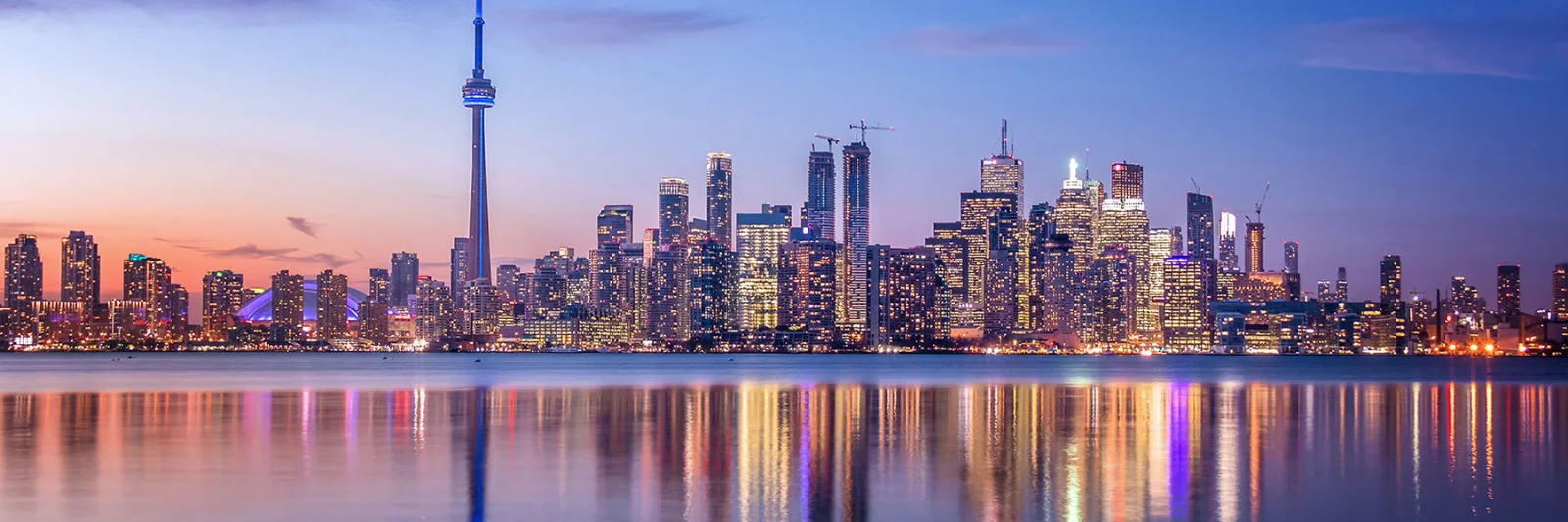 City skyline at dusk with reflections on the water, symbolizing stability and the future of the insurance industry.