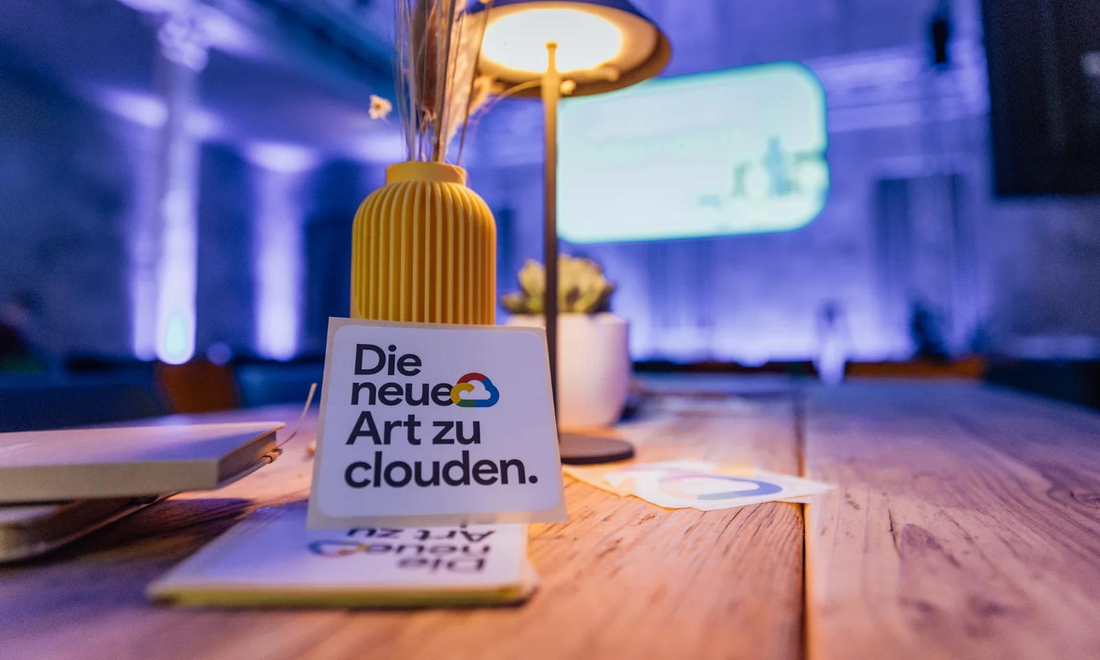 Nahaufnahme eines Tisches mit dem Schriftzug „Die neue Art zu clouden“ in einem atmosphärisch beleuchteten Raum auf dem Google Cloud Summit.