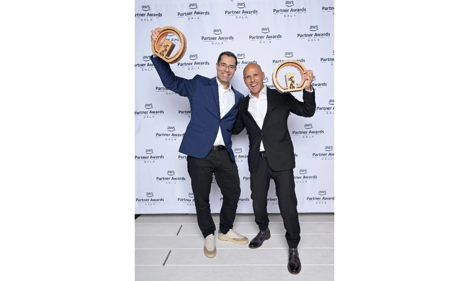 Two men celebrating and holding AWS Partner Awards trophies at the AWS Partner Awards Gala, symbolising GFT&#039;s recognition for outstanding partnership with AWS.