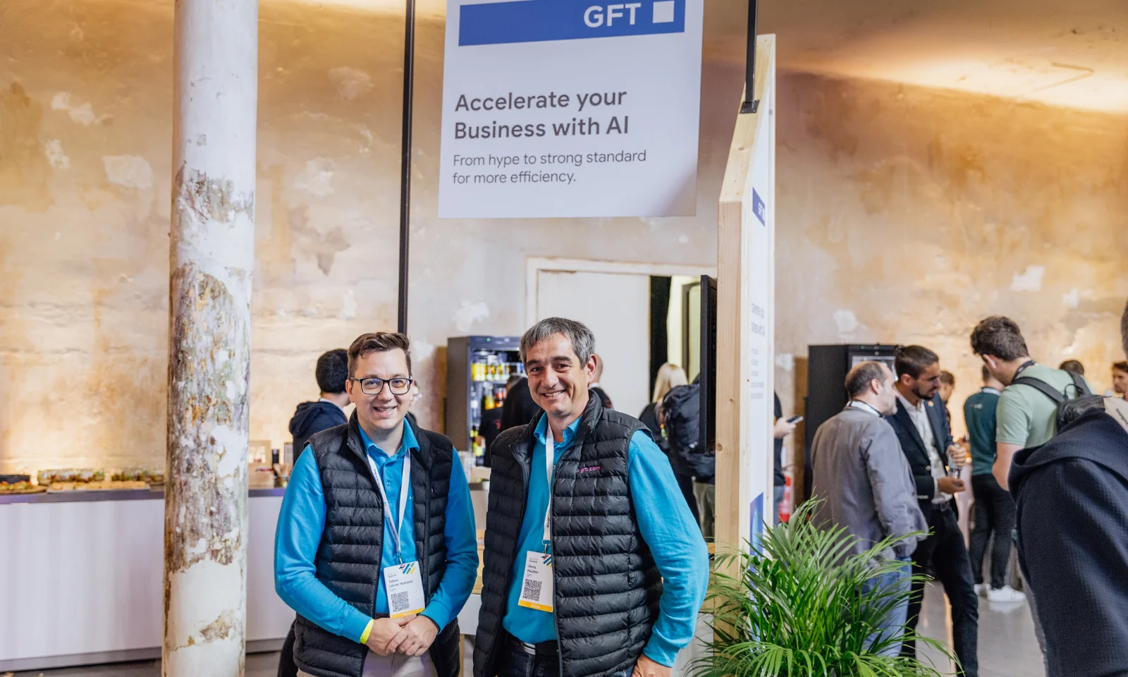 Zwei Mitarbeiter von GFT stehen am Stand auf dem Google Cloud Summit 2024 unter dem Motto „Accelerate your Business with AI“.