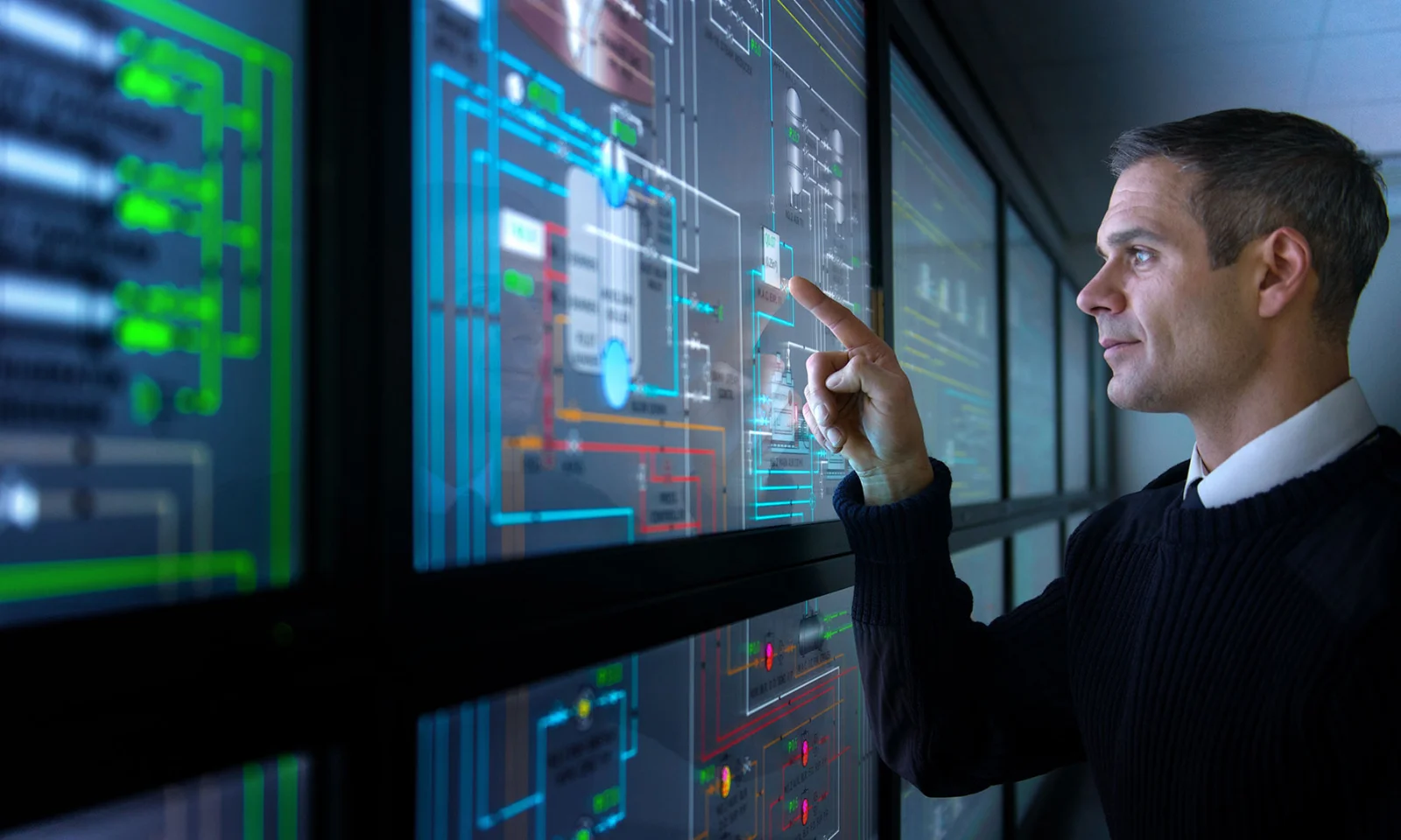 A professional interacts with a large, multi-screen digital interface displaying complex system diagrams, highlighting smart facility management.