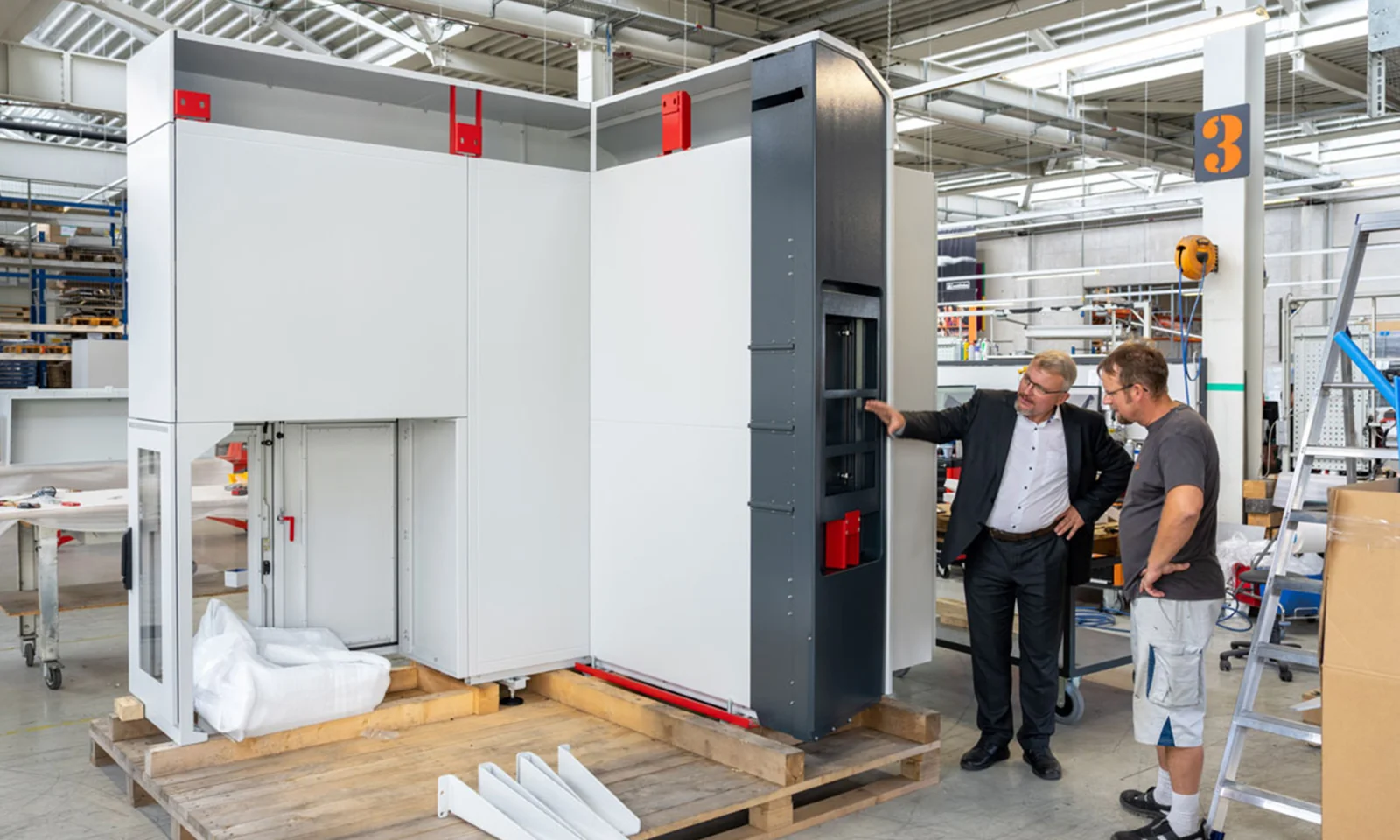 Two men discussing the details of a large industrial machine on the shop floor of Schinko, highlighting precision and attention to detail in manufacturing.