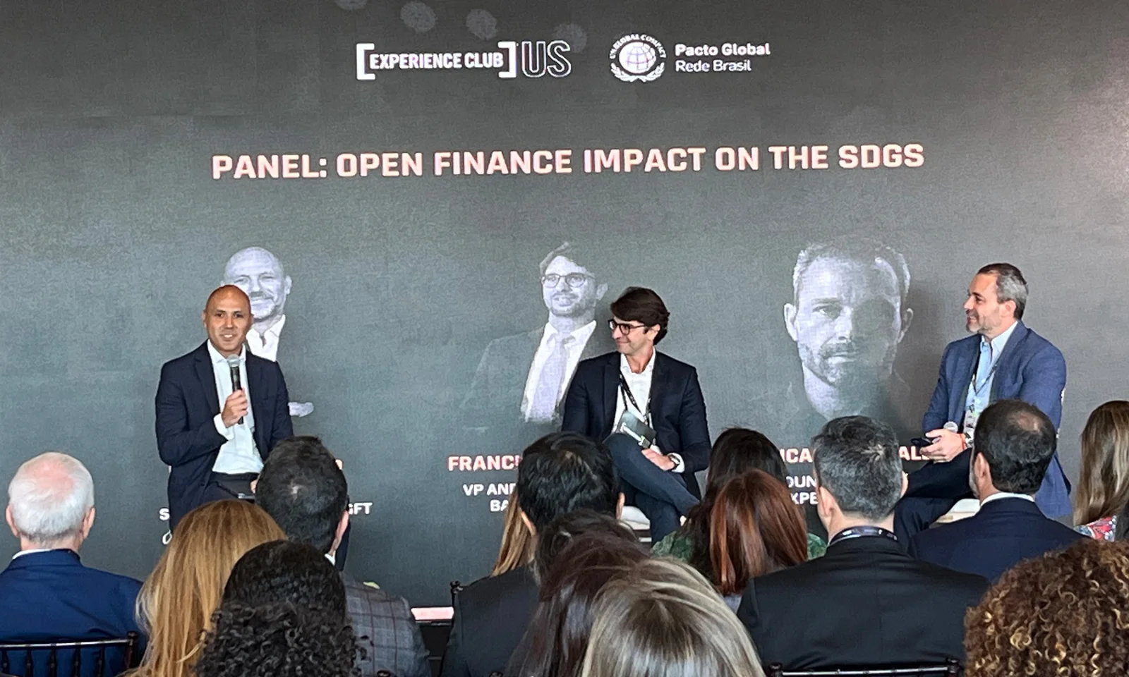 Panel discussion at the Experience Club event with three speakers discussing the impact of open finance on the Sustainable Development Goals (SDGs). Audience members are seated in the foreground.