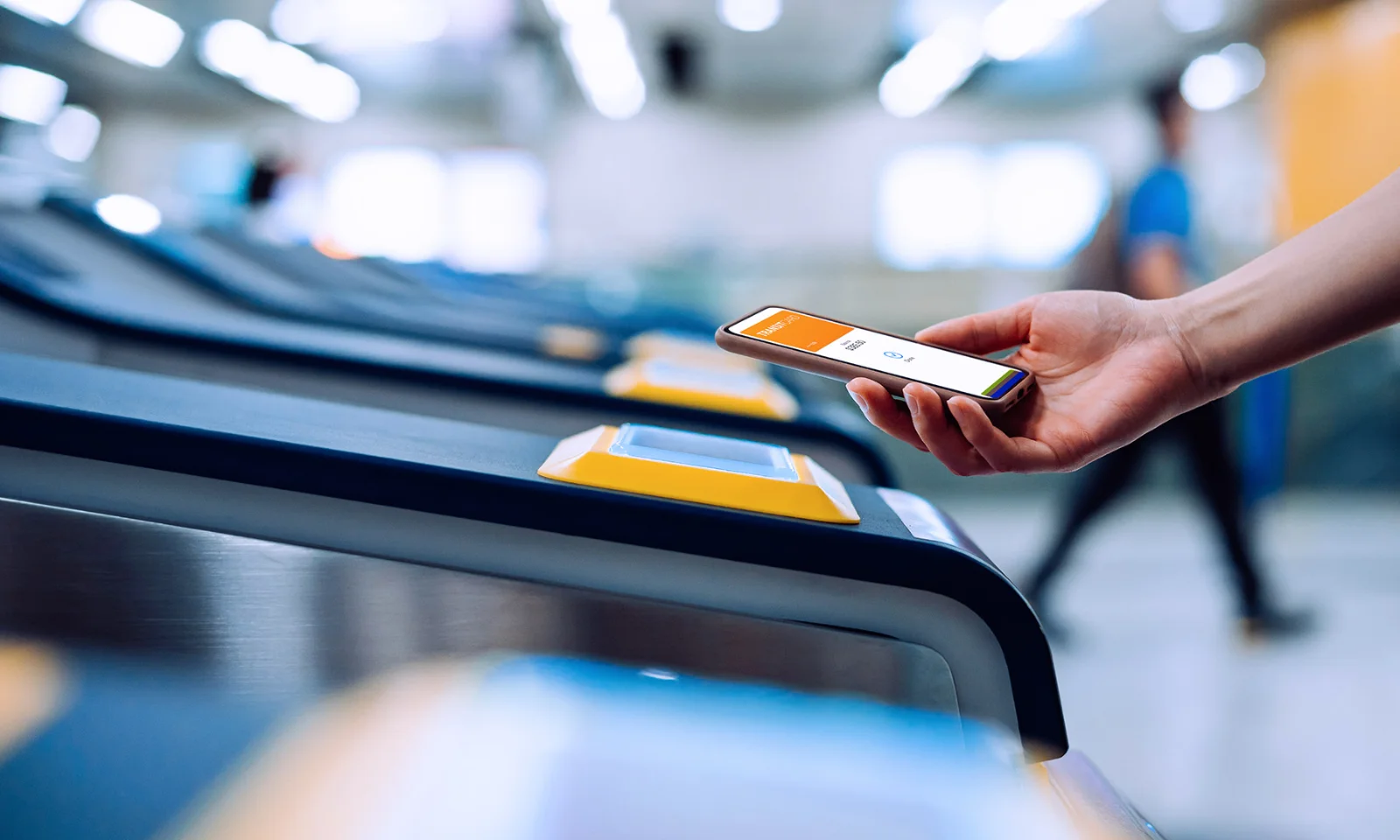 Hand holding a smartphone using a mobile ticketing app to access a transit gate, highlighting contactless payment technology.