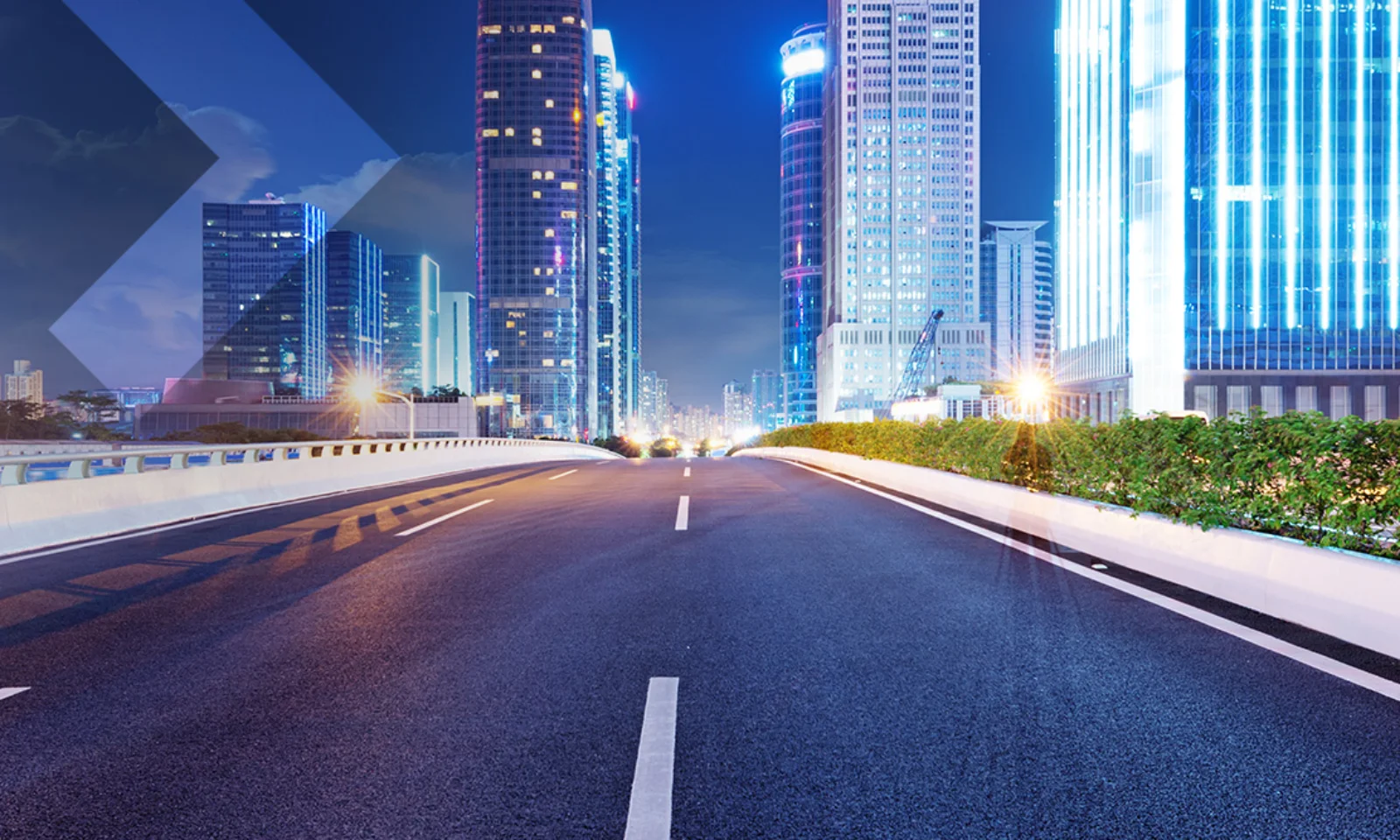 Empty urban road leading into a cityscape with brightly lit skyscrapers at night, symbolizing innovation and the future of urban development.