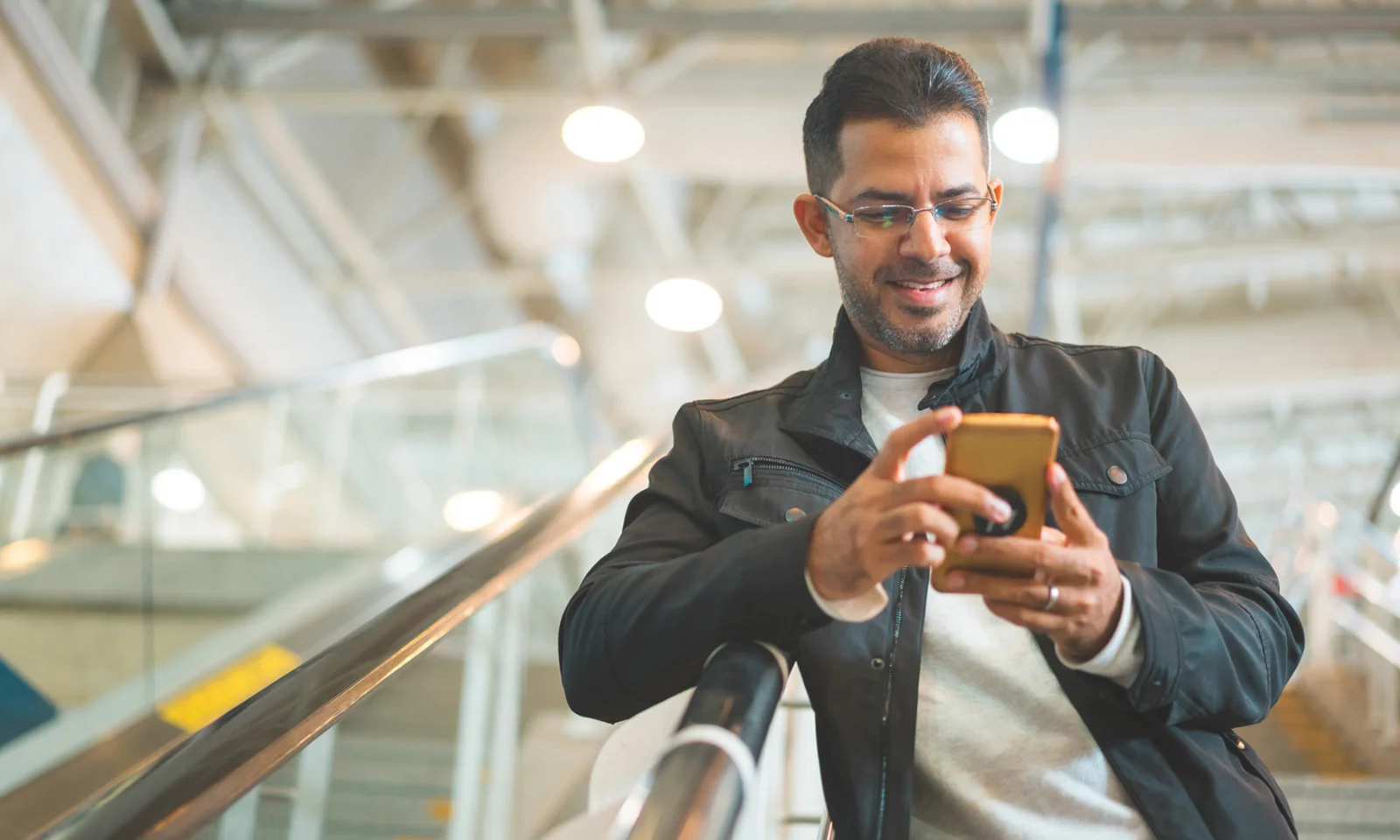 A man smiling while using his smartphone, representing the impact of banking disruption and modern digital services.