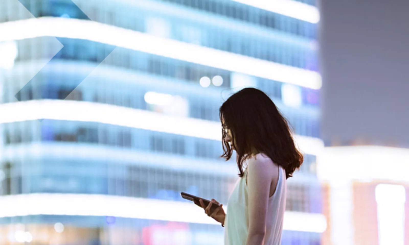 A professional woman using her smartphone with a modern cityscape in the background, symbolizing the impact of Central Bank Digital Currencies (CBDCs) on the future of commercial banking.