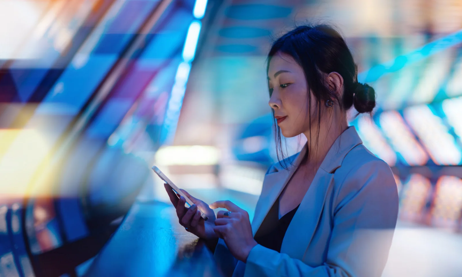 A woman in a business suit uses her smartphone, surrounded by vibrant, abstract digital colours, symbolising the connected and dynamic nature of digital banking.