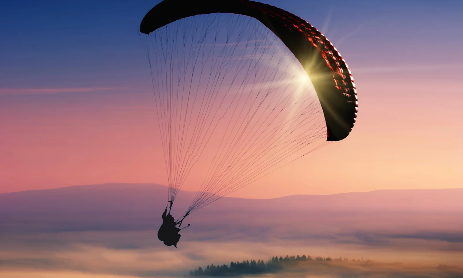 Uma silhueta de tirar o fôlego de um parapente voando em um vibrante céu de pôr do sol, simbolizando a liberdade, a agilidade e as possibilidades expansivas oferecidas por soluções híbridas e multinuvem.