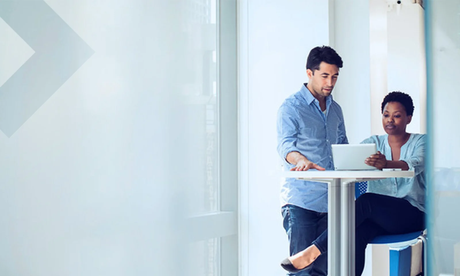 Two colleagues collaborating on a project while working on a laptop in a bright, modern office setting.