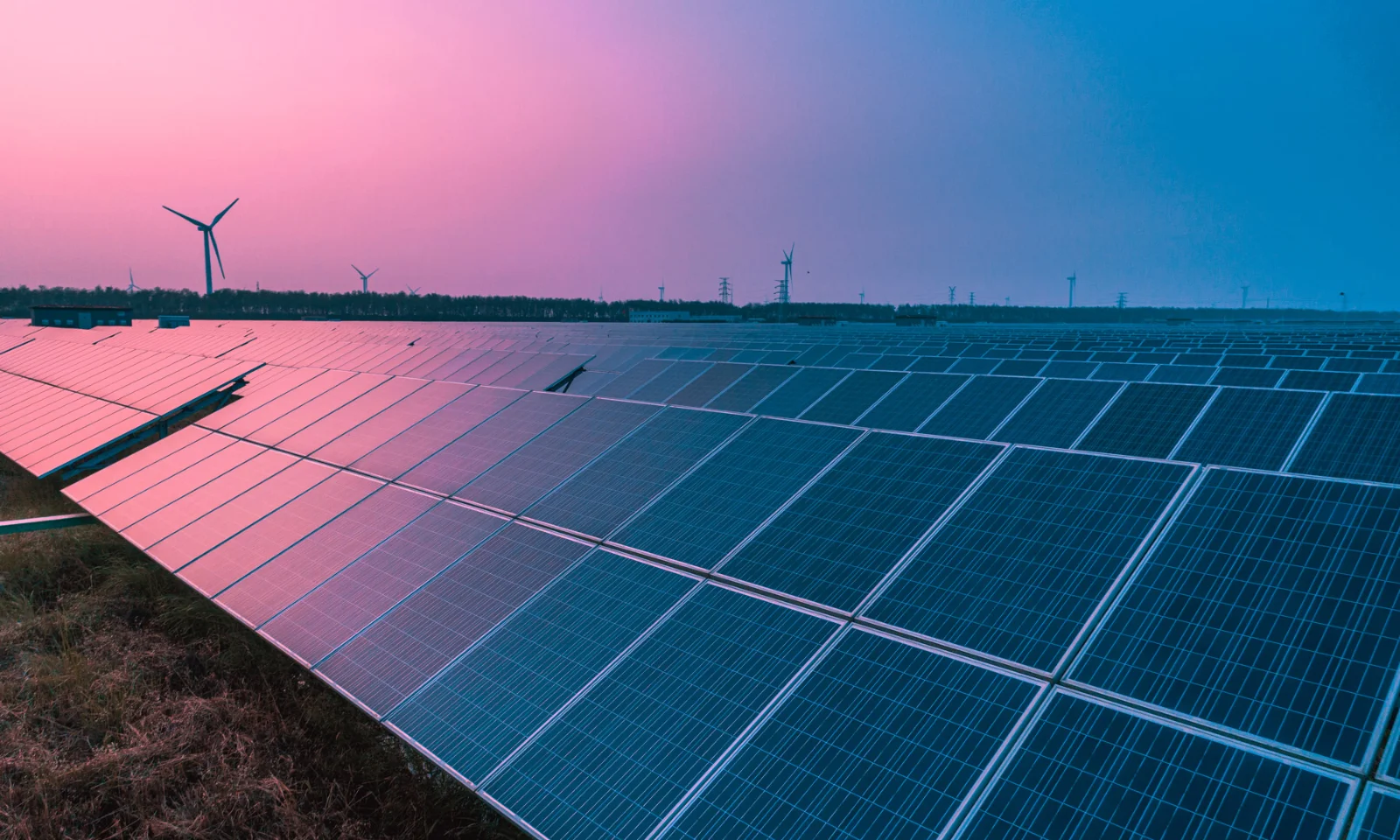 Solar panels and wind turbines at sunset, illustrating GFT’s commitment to reducing greenhouse gas emissions and achieving its SBTi-approved climate targets.