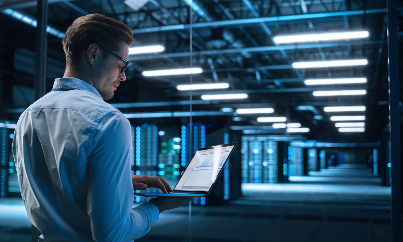 A professional working on a laptop in a high-tech data centre, symbolising the concept of data virtualisation and modern data management solutions.