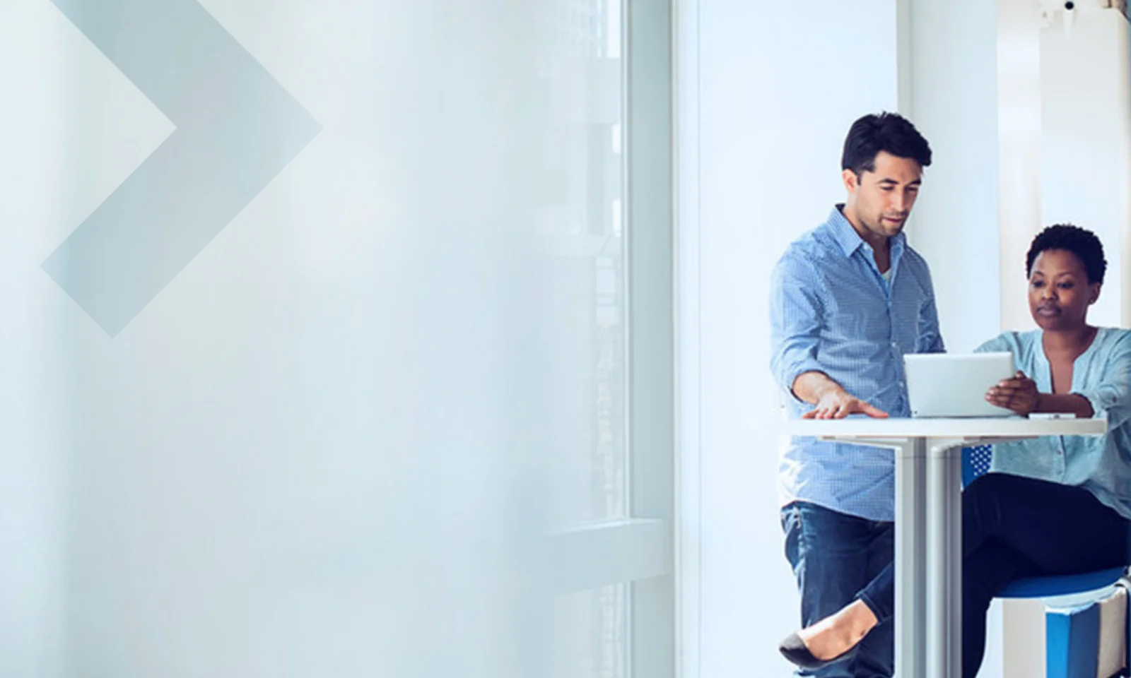 Two colleagues collaborating on a project while working on a laptop in a bright, modern office setting.