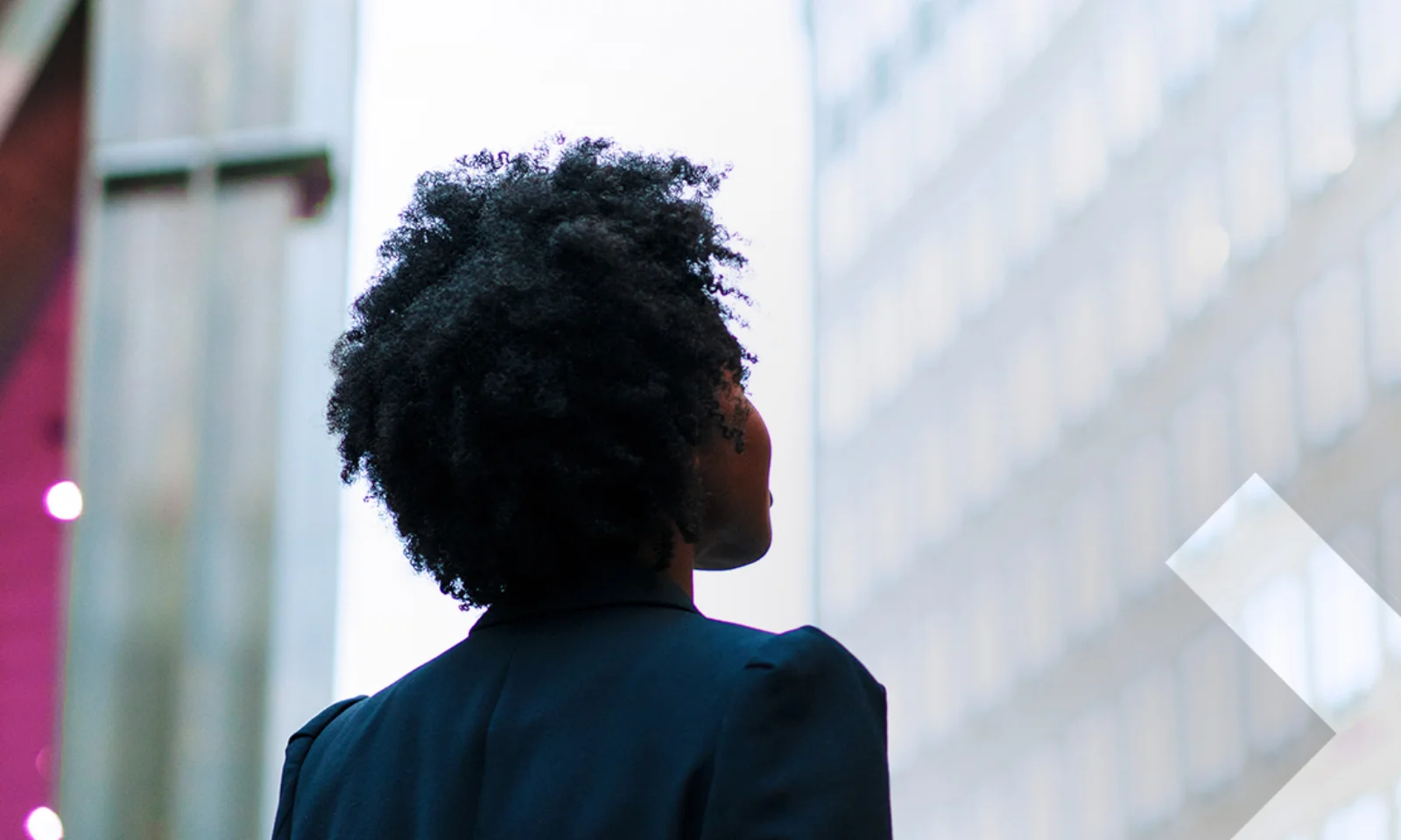 Headerbild zeigt eine Person von hinten, die vor modernen Gebäuden steht. Symbolbild für Veränderungen, Effizienz und Innovation durch T+1 im Finanzsektor.